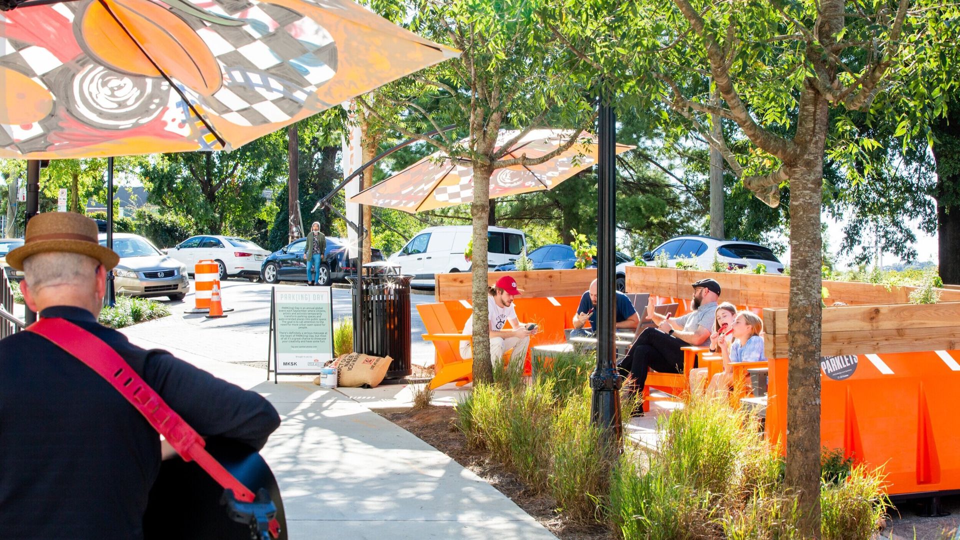 A group of people sit at an outdoor seating area made from two unused parking spaces