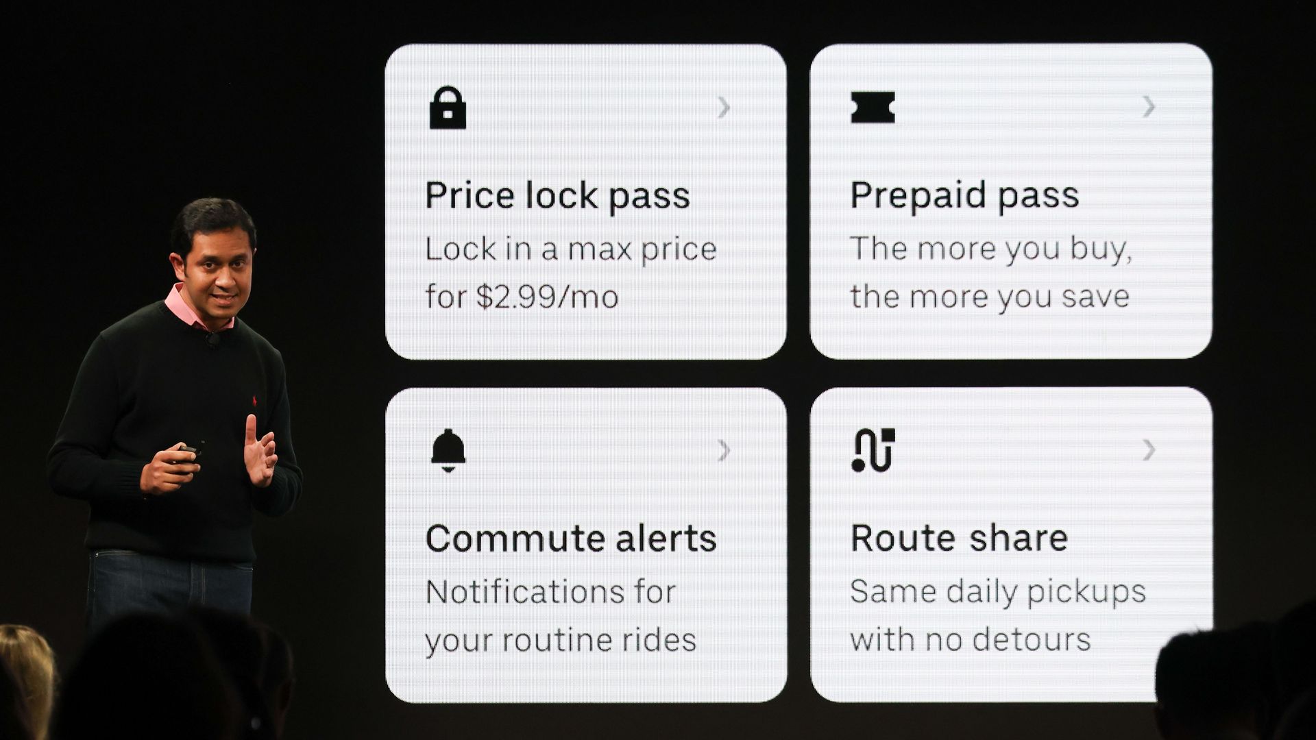 Sachin Kansal, Uber chief product officer, speaks during Uber's event Wednesday about new features. On the screen to the right of him it says price lock pass, prepaid pass, commute alerts and route share.