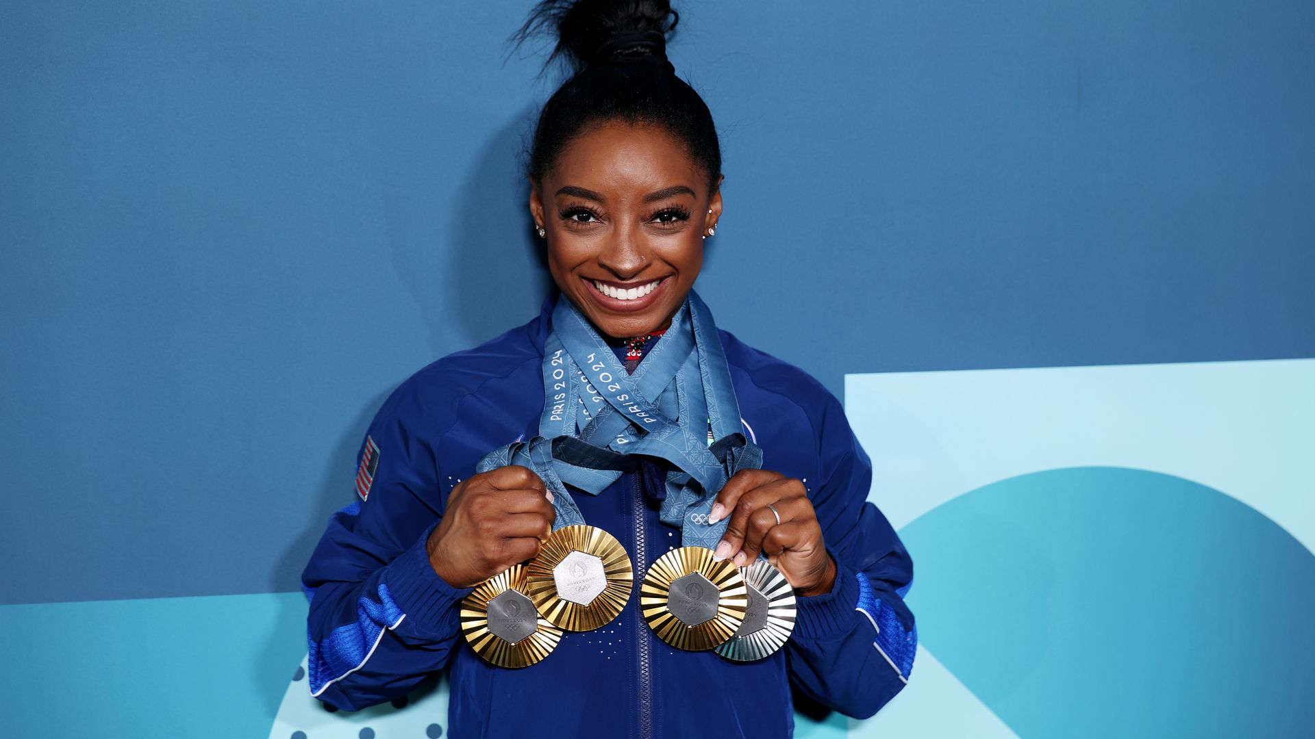 Simone Biles poses with several Olympic medals