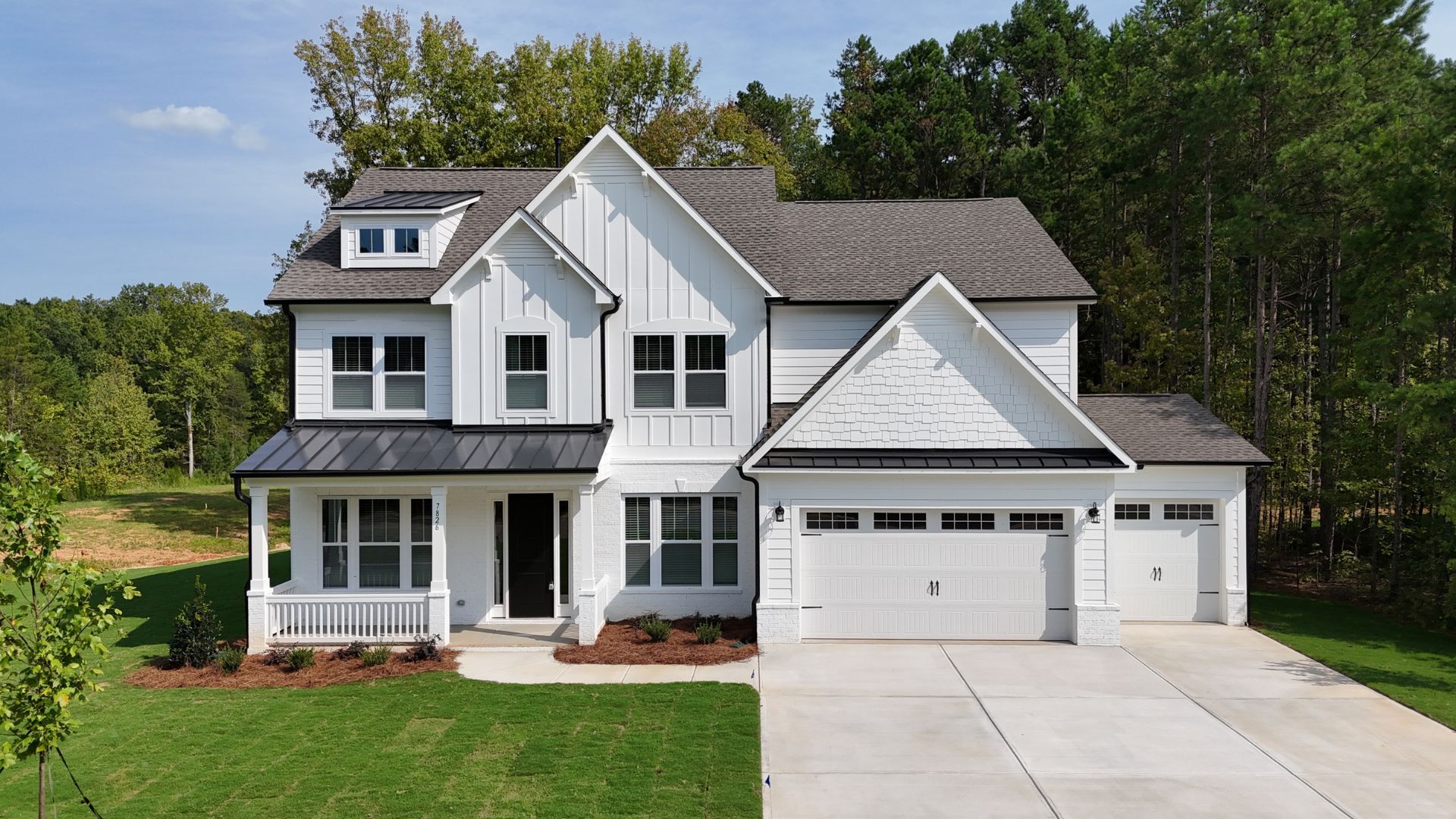 Modern farmhouse with white siding, black accents and a three-car garage.