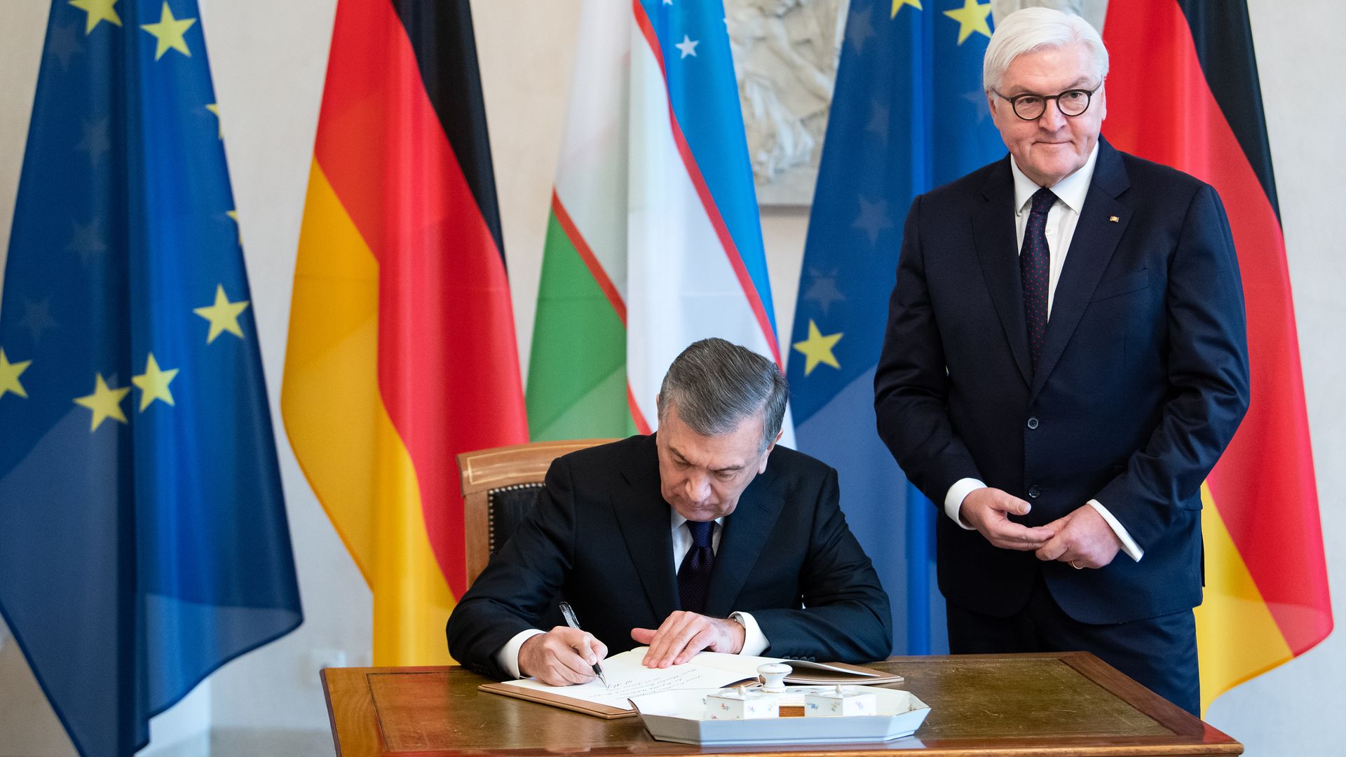 Shavkat Mirsiyoyev, President of Uzbekistan, in the presence of Federal President Frank-Walter Steinmeier (r), signs the guest book of Bellevue Castle.
