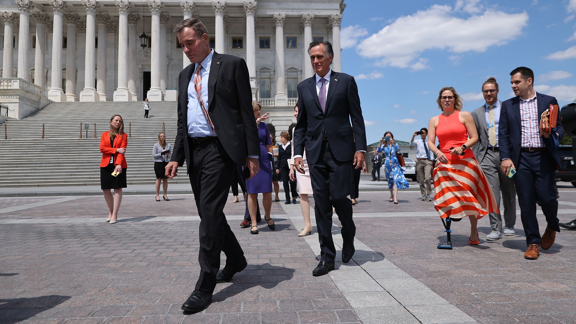 Sens. Mark Warner, Mitt Romney and Krysten Sinema are seen leaving the Capitol for a meeting with President Biden.