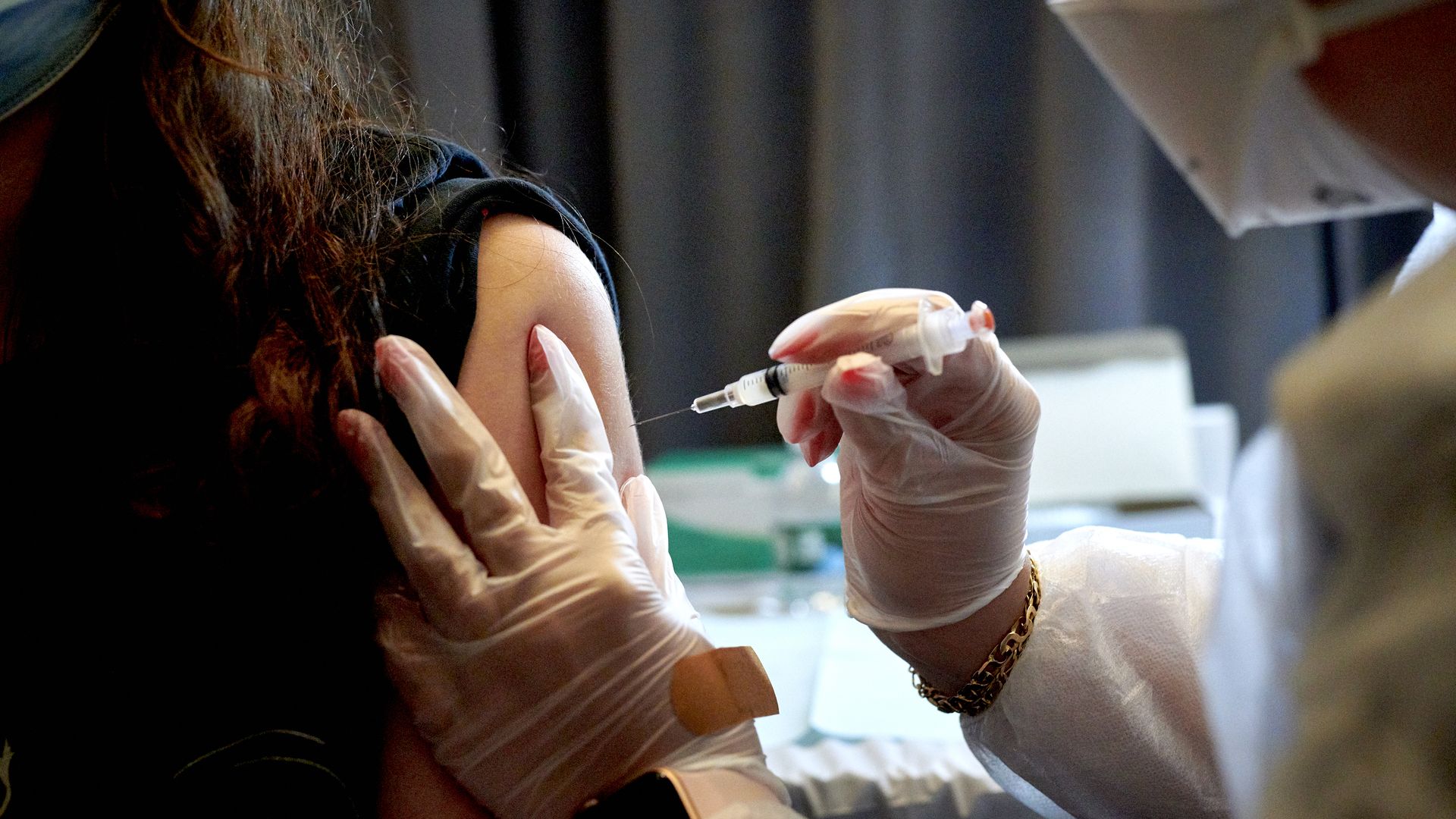 Photo of a medical worker administering a COVID vaccine to a person with their sleeve up
