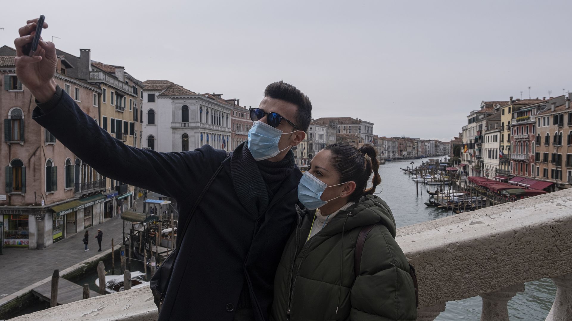Tourists with protective face masks take a selfie on the Rialto Bridge on March 06, 2020 in Venice, Italy.