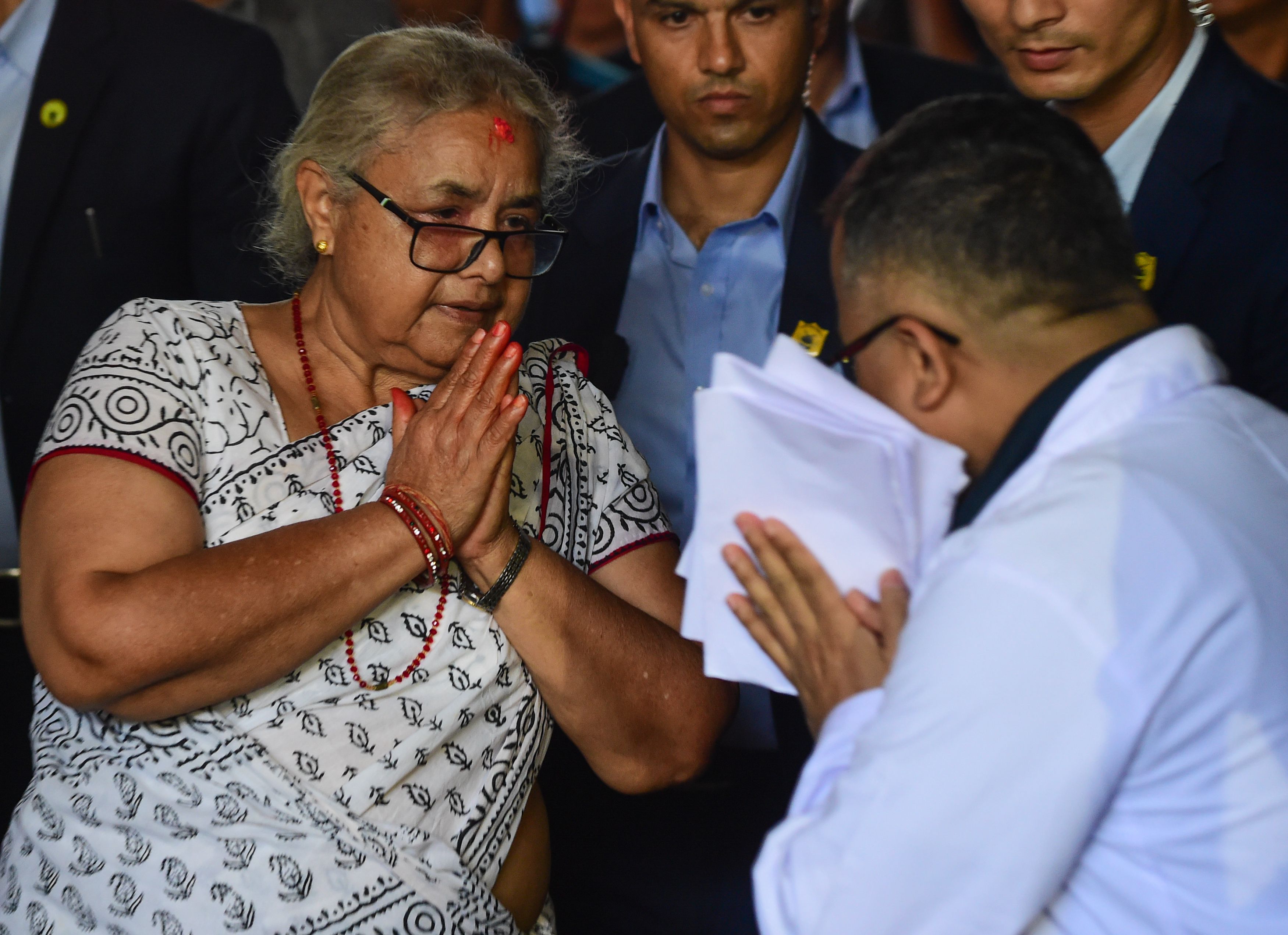A woman in a white sari greets a doctor