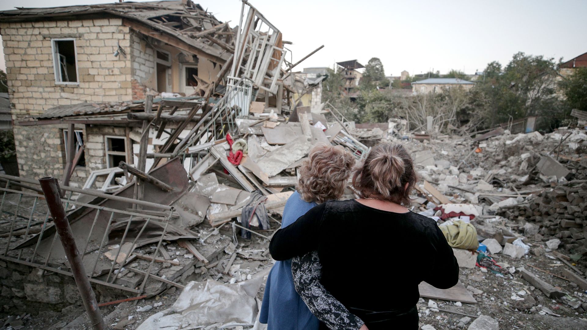 Women embrace as they examine the ruins of a residential house destroyed in a shelling attack