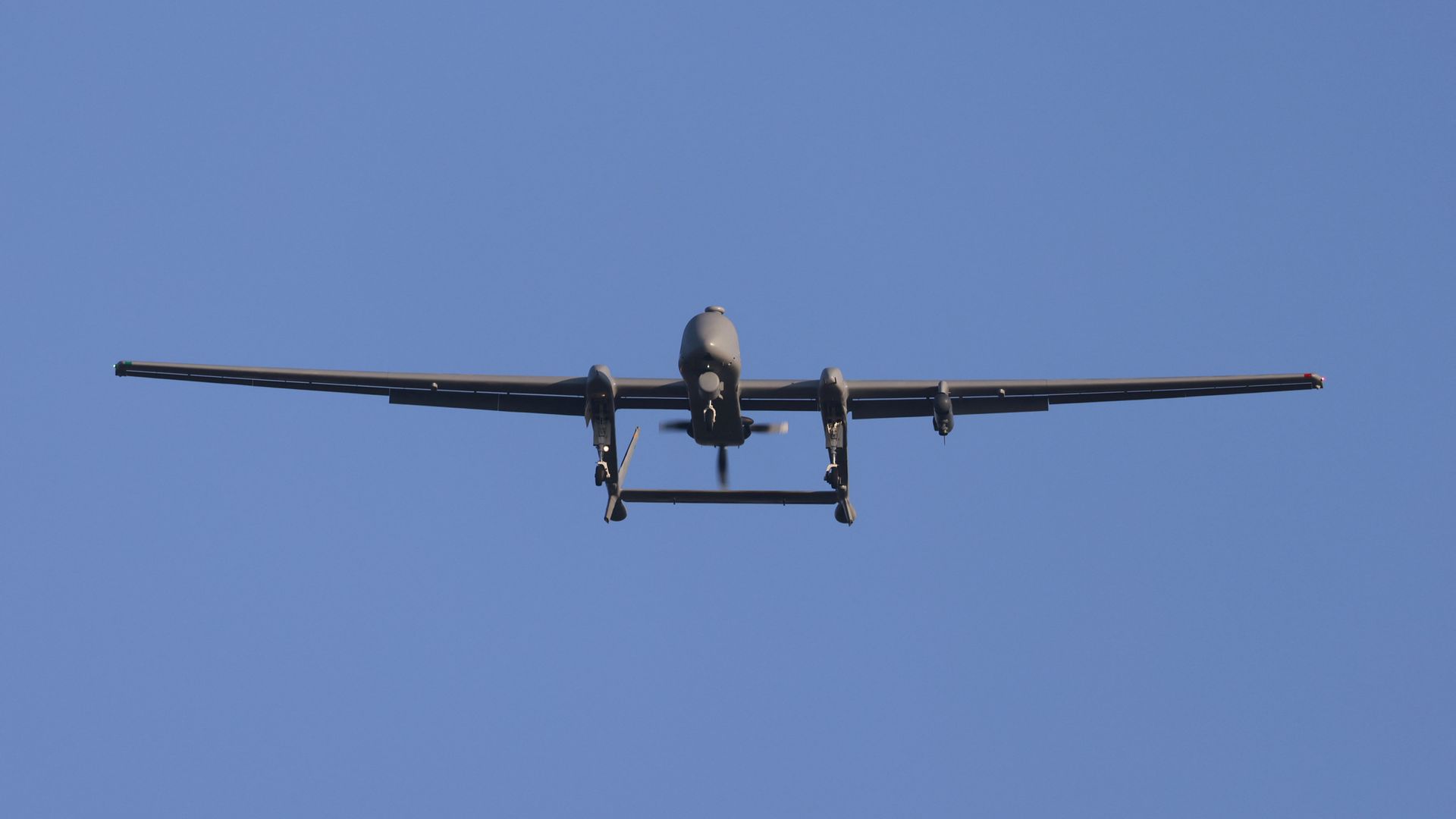 A large drone flies through blue skies.