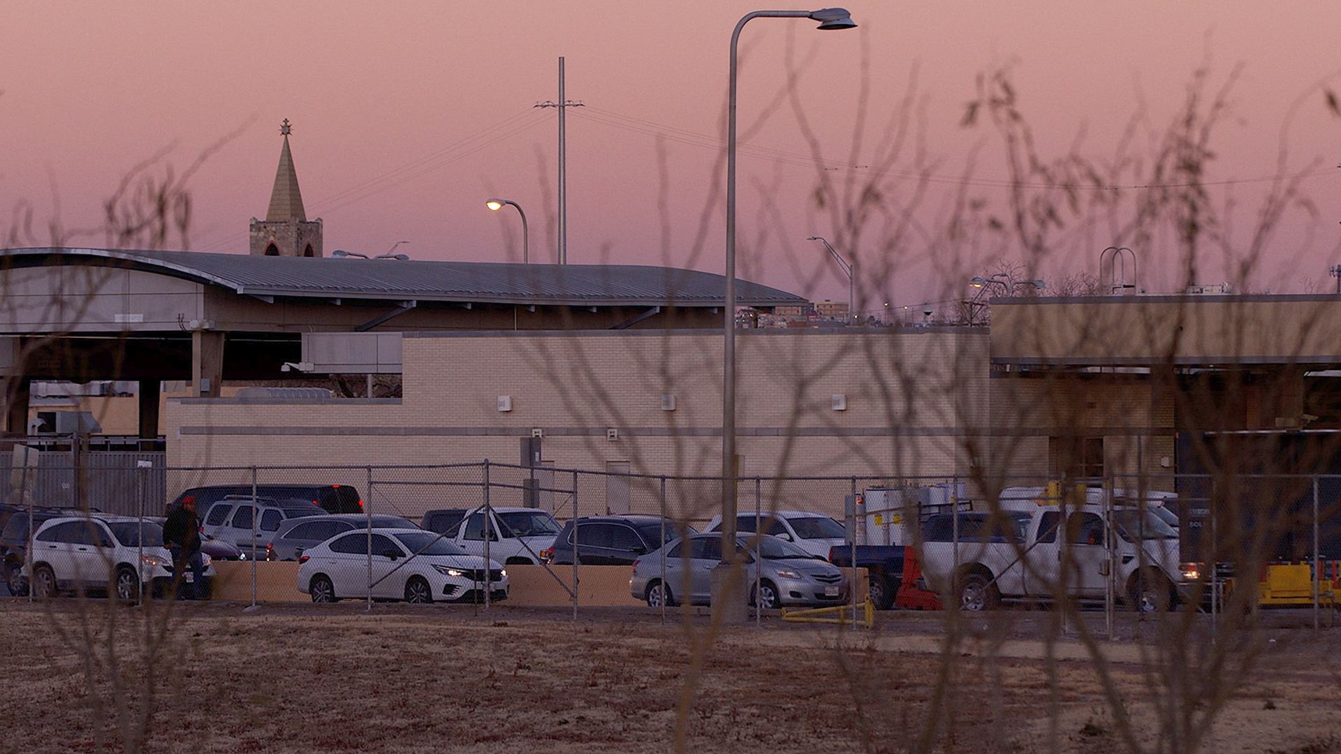 Smog and an off-pink sky are shown in this picture of El Paso, Texas, which also includes parked cars and a lamp post