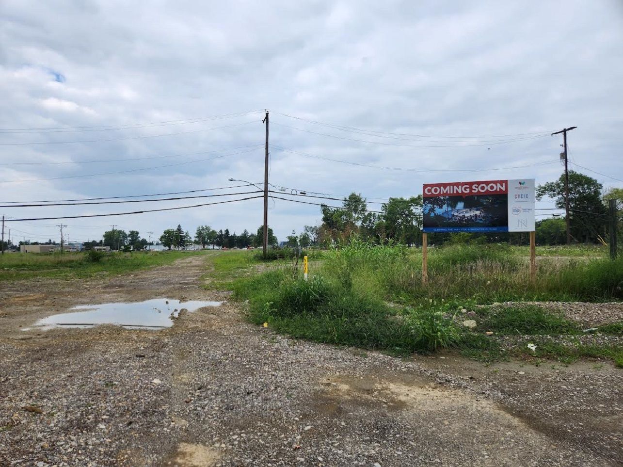 An open field with a "Coming Soon" sign previewing future development.