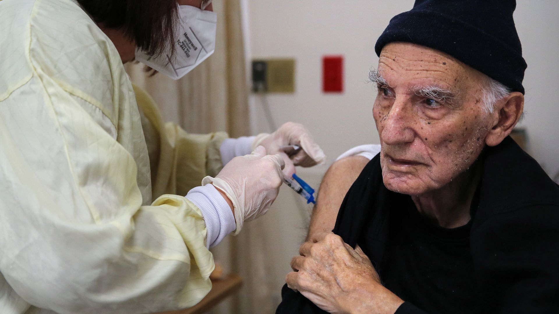 Photo of a person wearing a black hat getting the Moderna vaccine from a masked health care worker