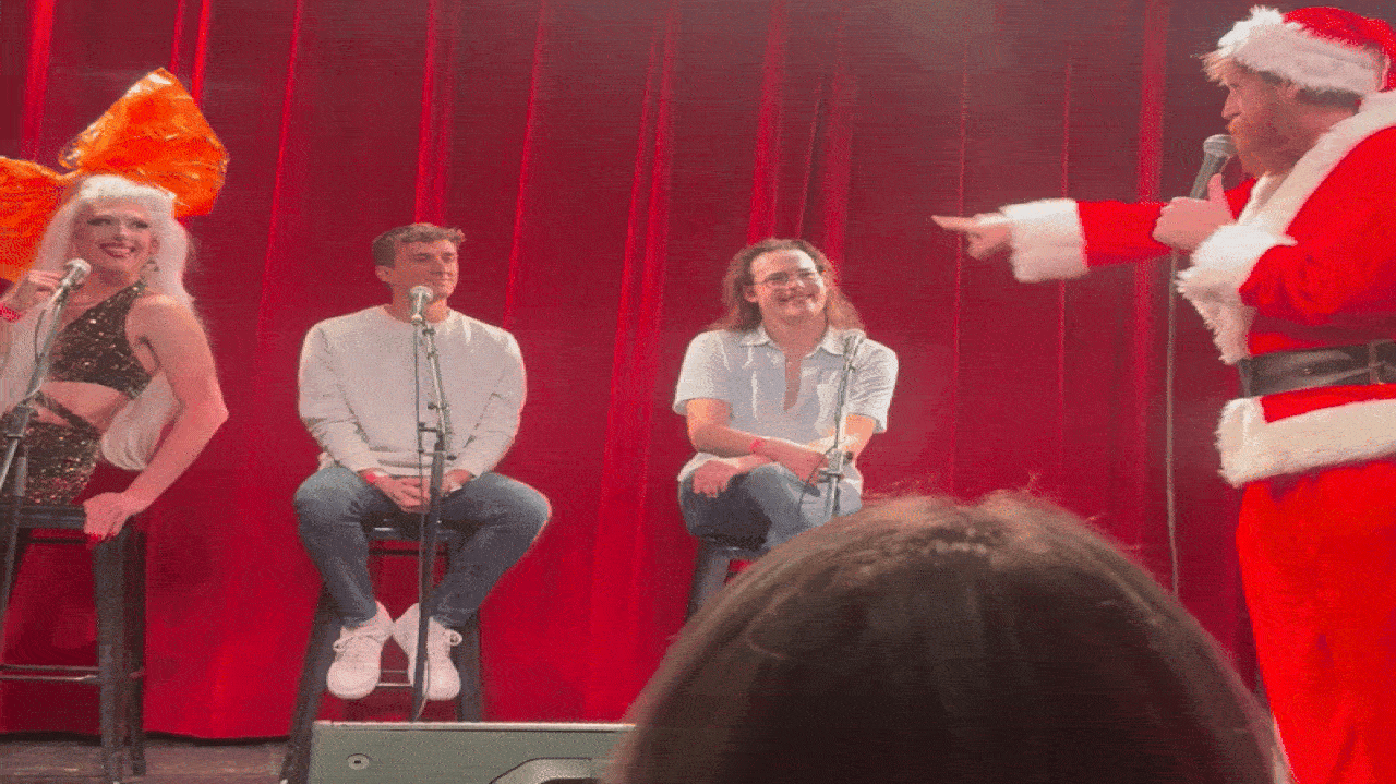 Santa announcing who is on the nice list at That KC Dating Show.