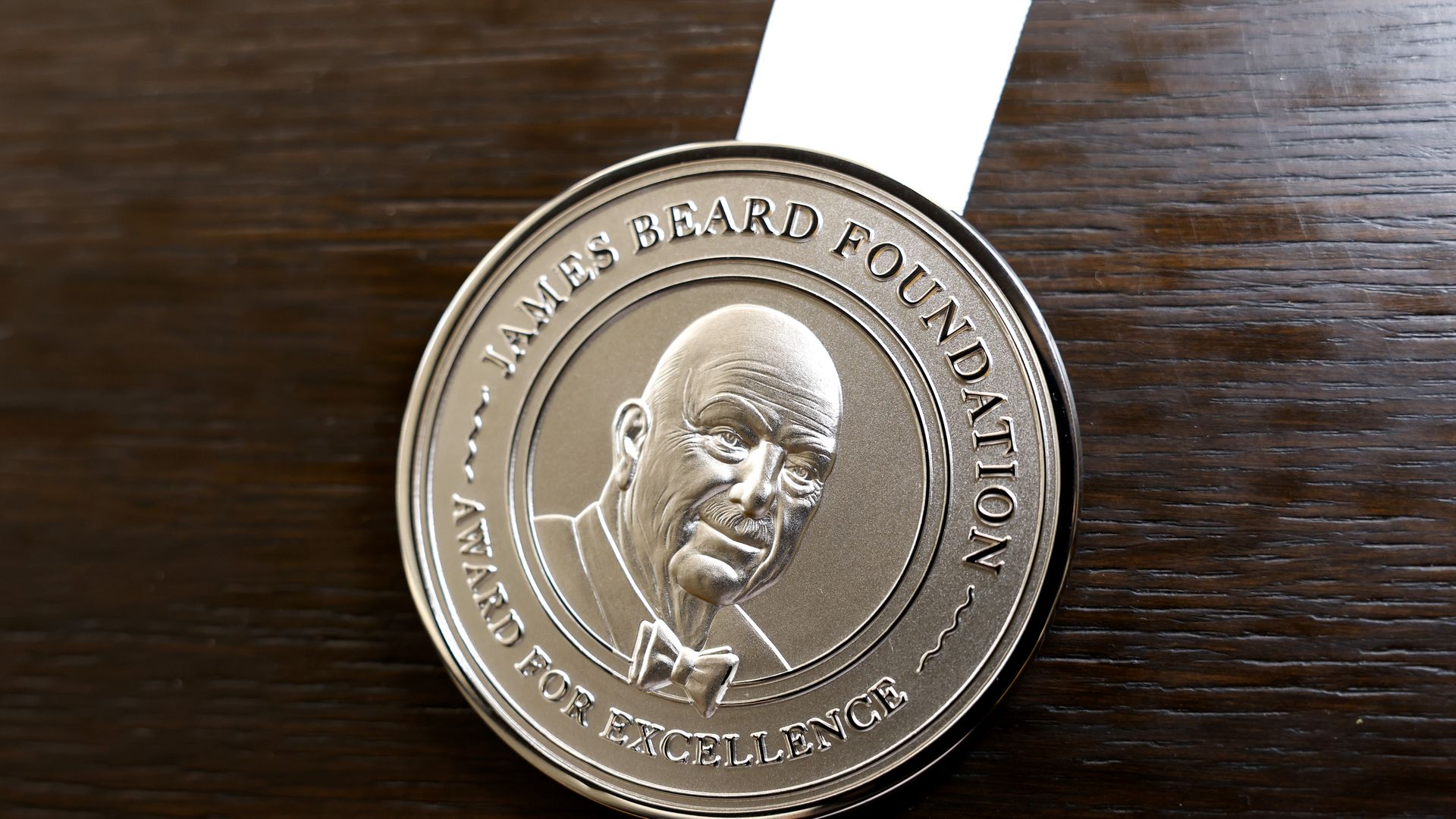 A medal inscribed with "James Beard Foundation" and a illustration of Beard.
