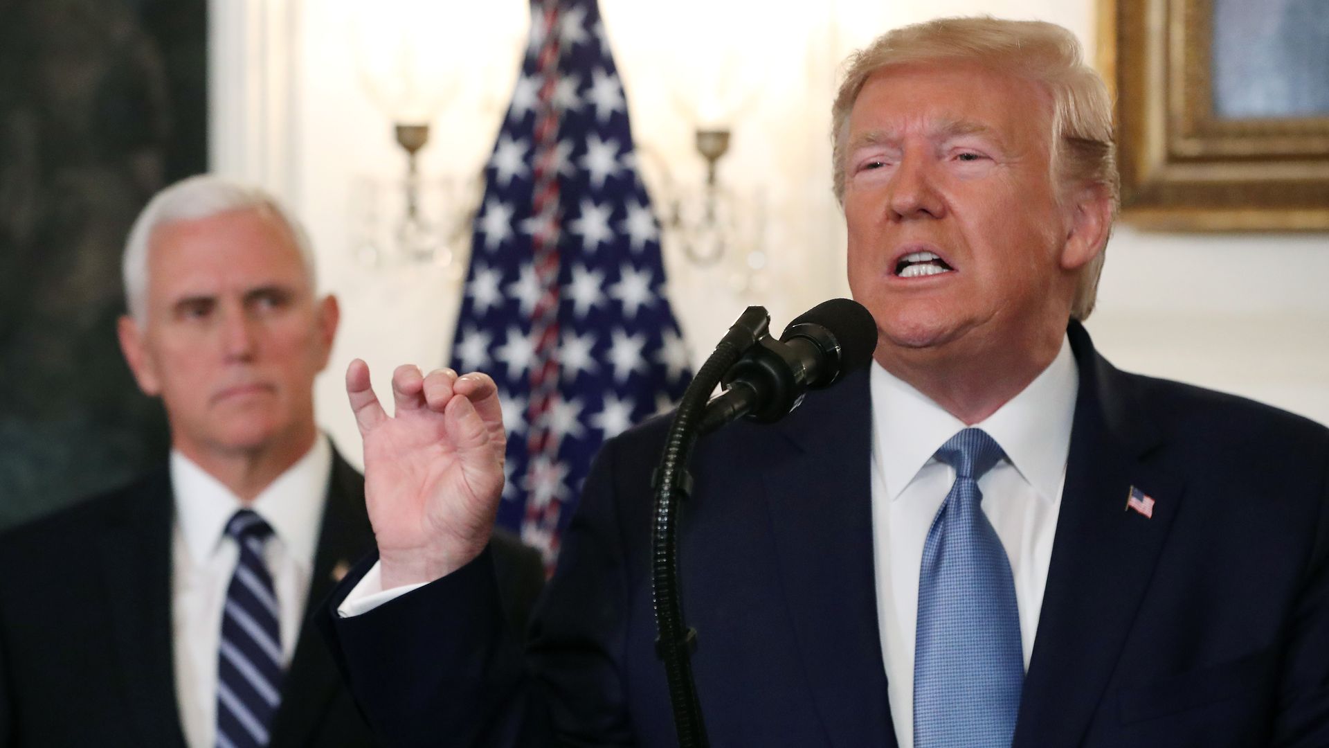 In this image, Trump speaks into a microphone with Pence behind him.