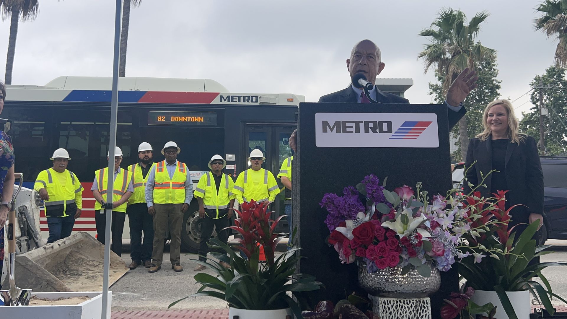 Mayor John Whitmire speaks as a Metro bus is stopped behind him 