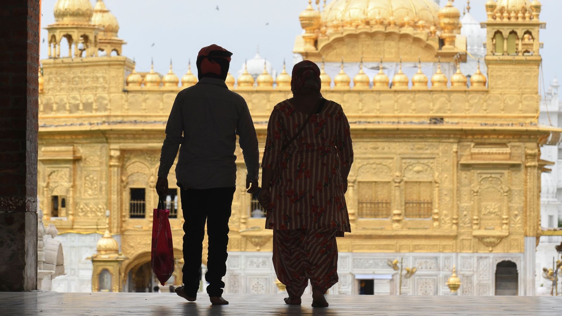 Two people walk through a doorway with a temple in the background