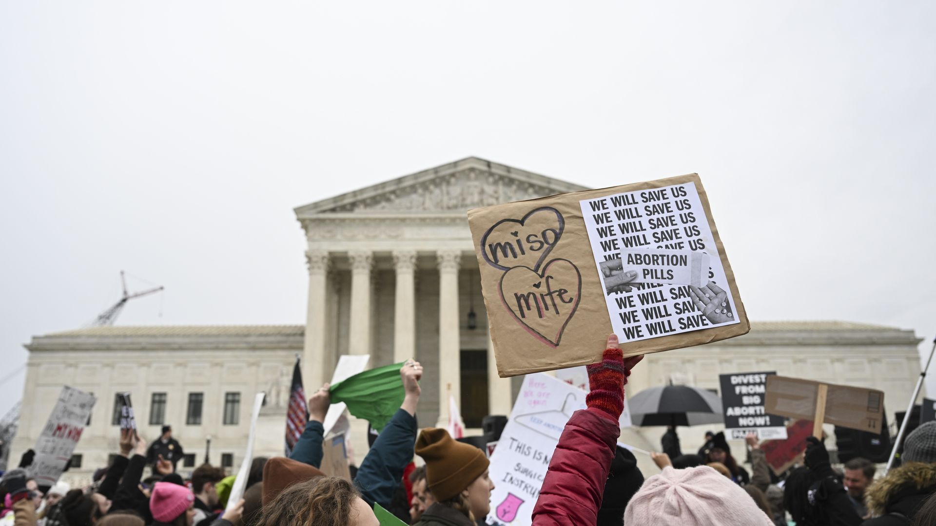 Picture of a person holding a sign that says "miso" and "mife" in an abortion rights protest in front of the Supreme Court building