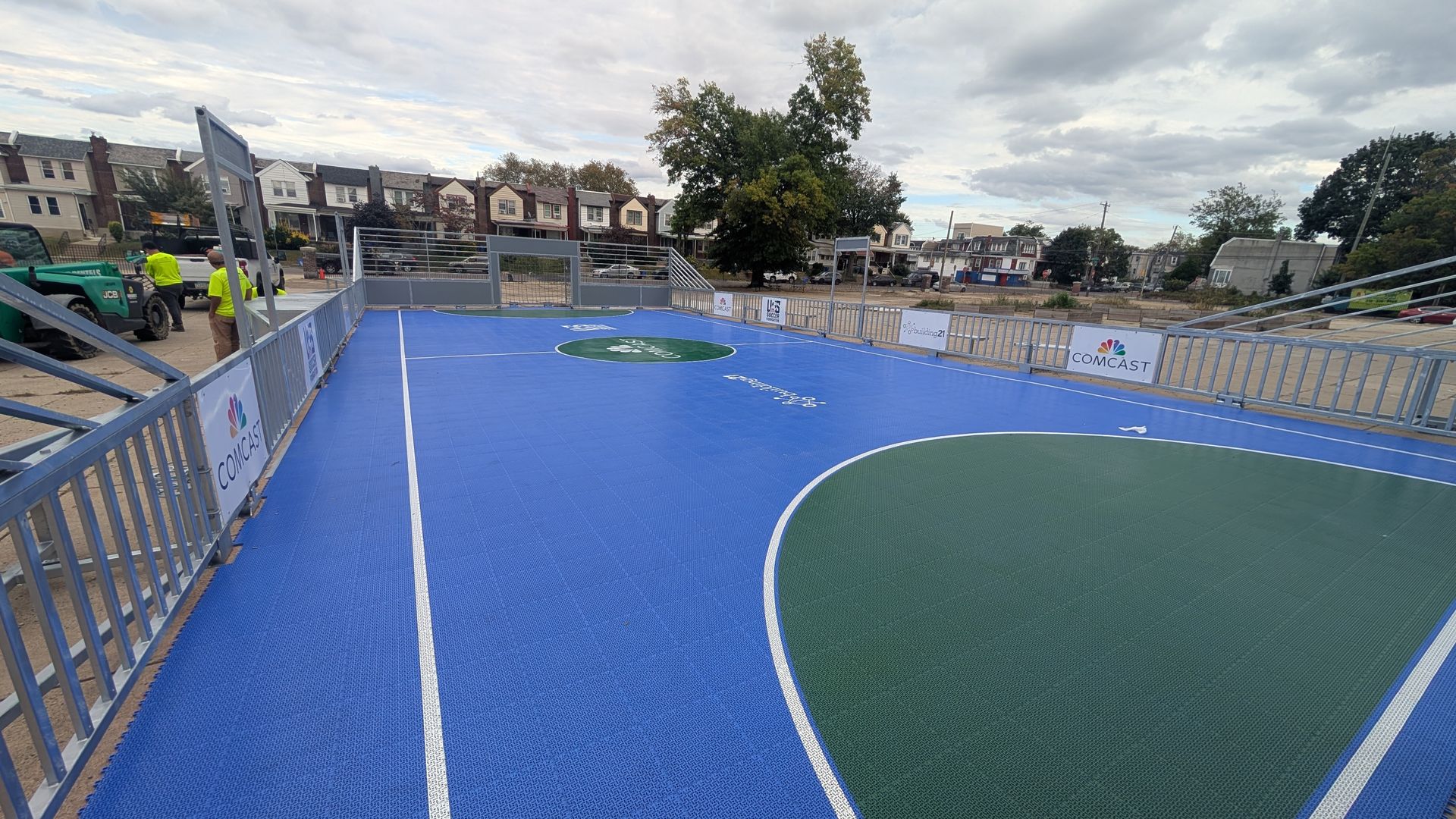A small soccer pitch painted blue and green with fencing around it. 