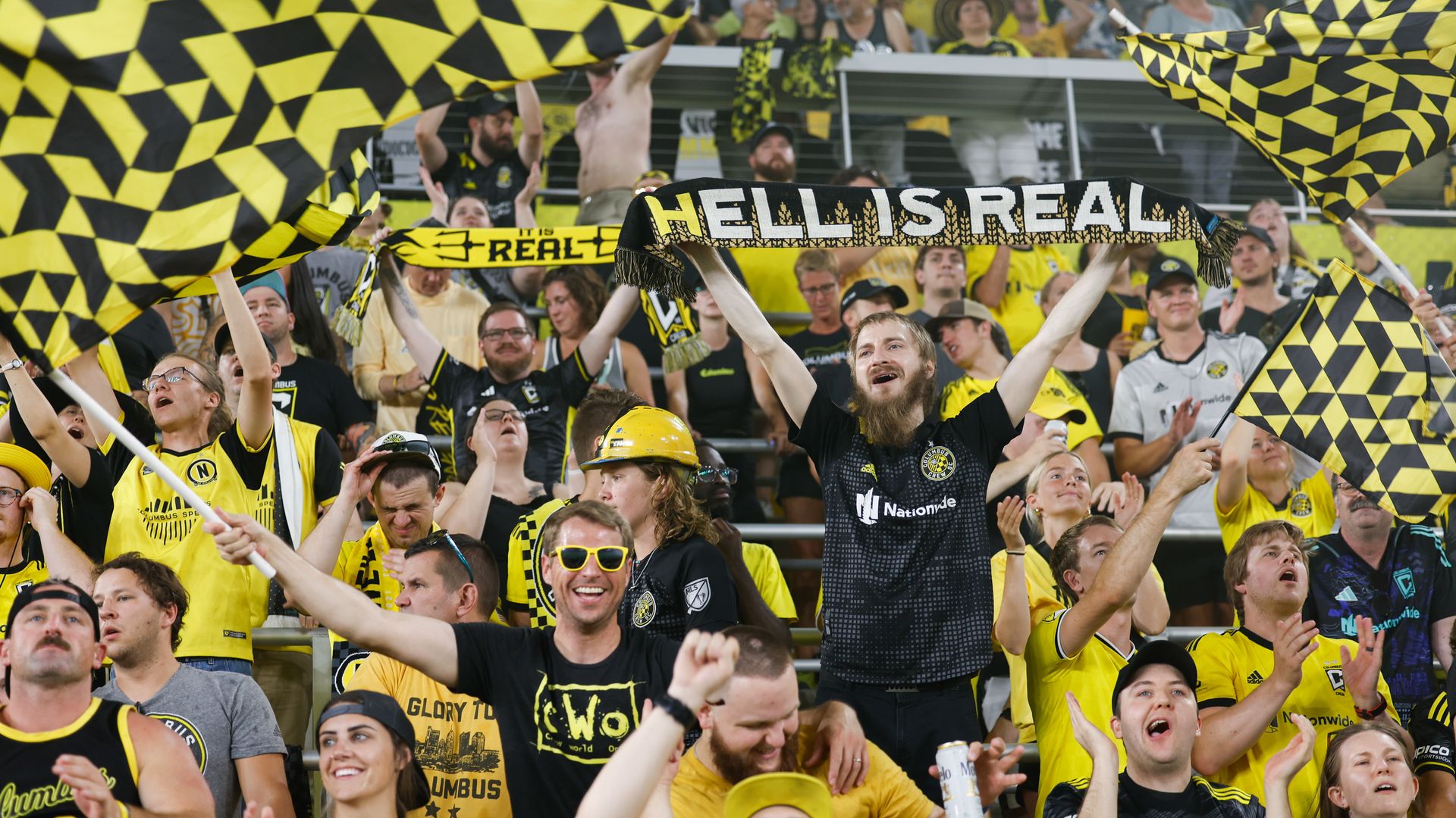 Columbus Crew fans cheering with one holding a banner reading "Hell Is Real."