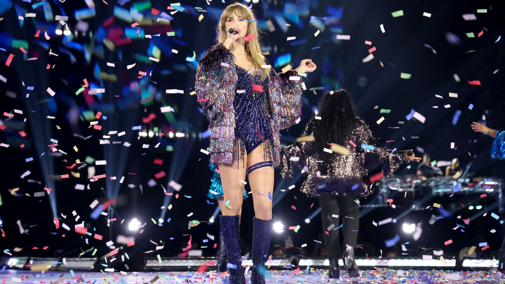 Taylor Swift sings on stage surrounded by confetti.