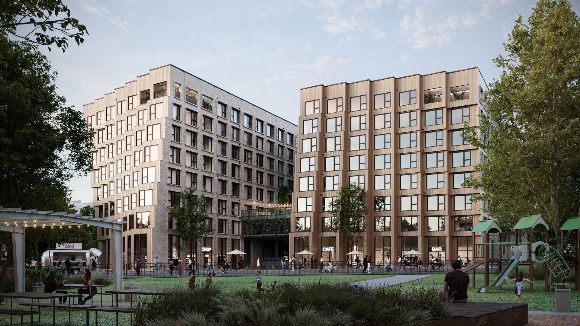 Two modern, mid-rise buildings with large windows frame a communal plaza and park. Ground-floor cafes and shops line the street; a playground and string lights sit in the foreground as people walk.