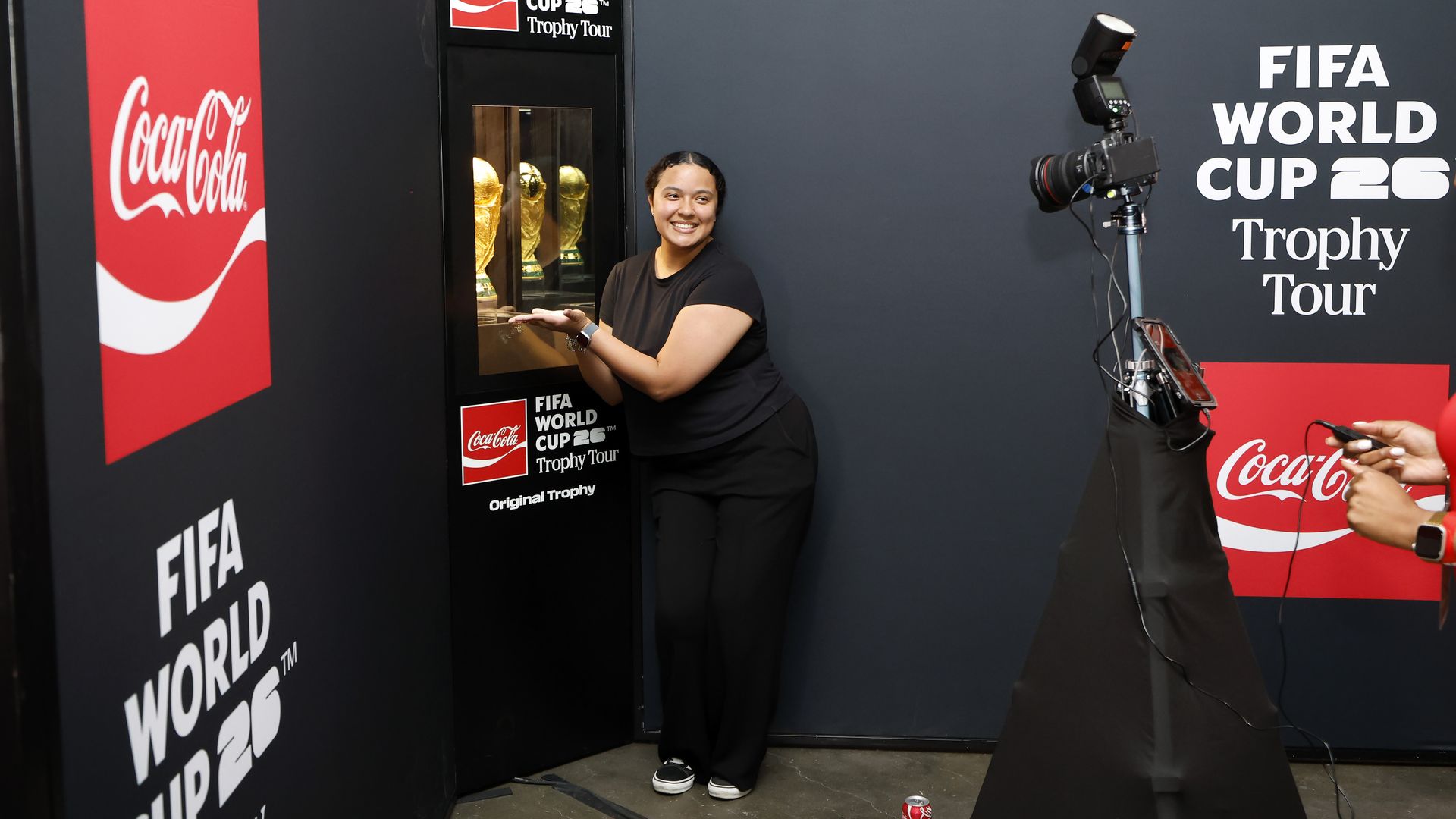 Image shows a woman posing with the FIFA World Cup trophy