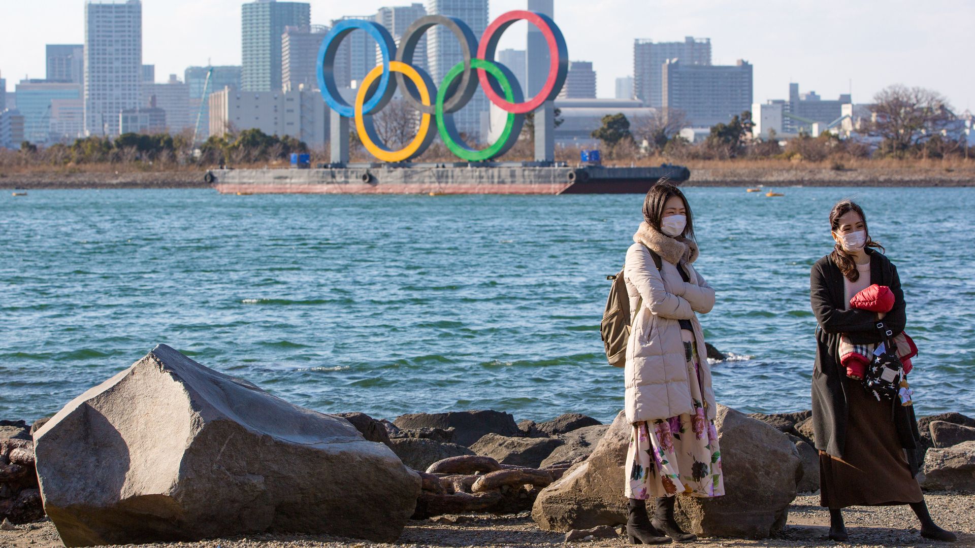 Olympic Rings installation in Odaiba Marine Park, Tokyo, as two women stand by. 