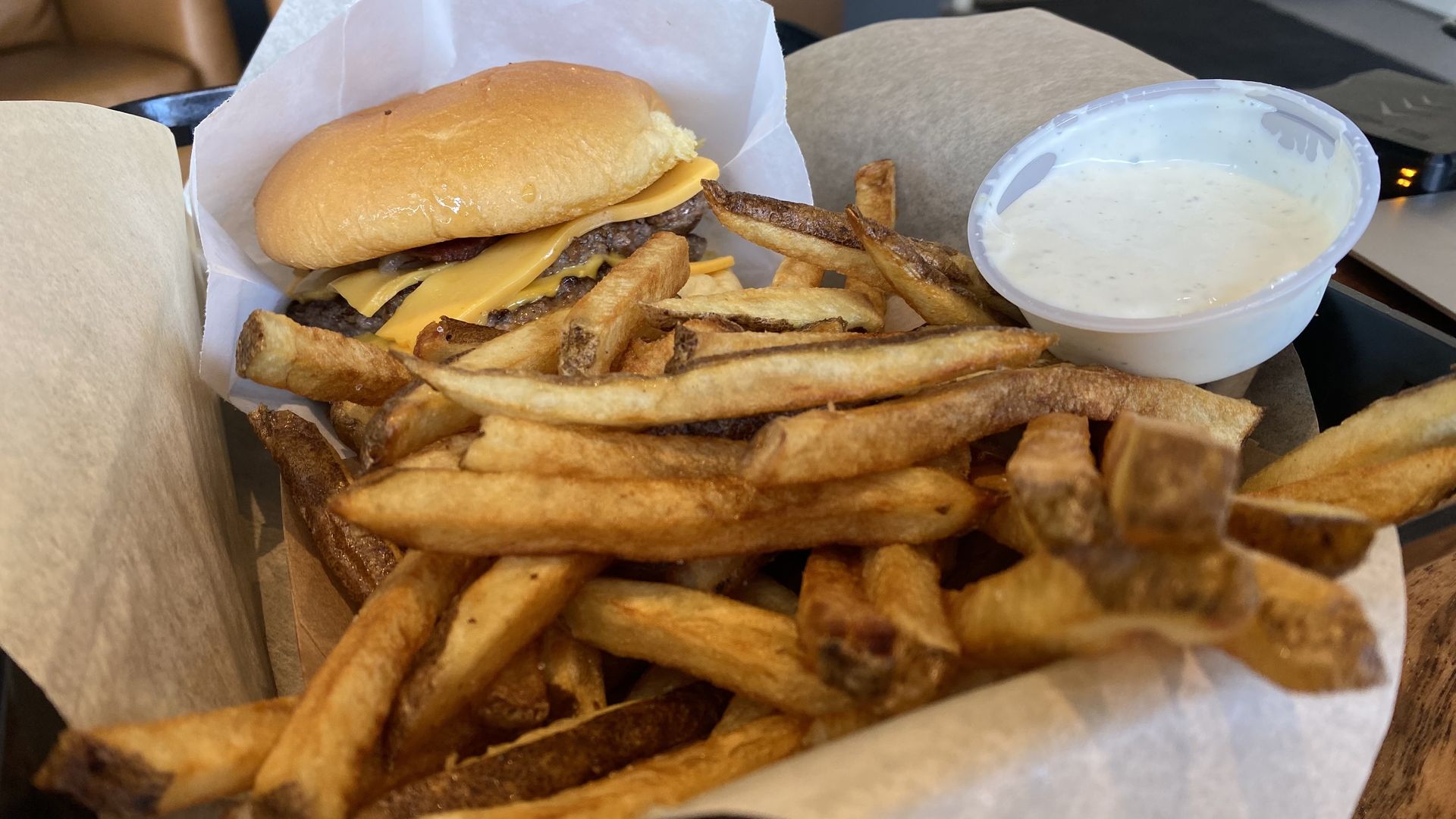 A photo of a burger and fries in a paper basket.