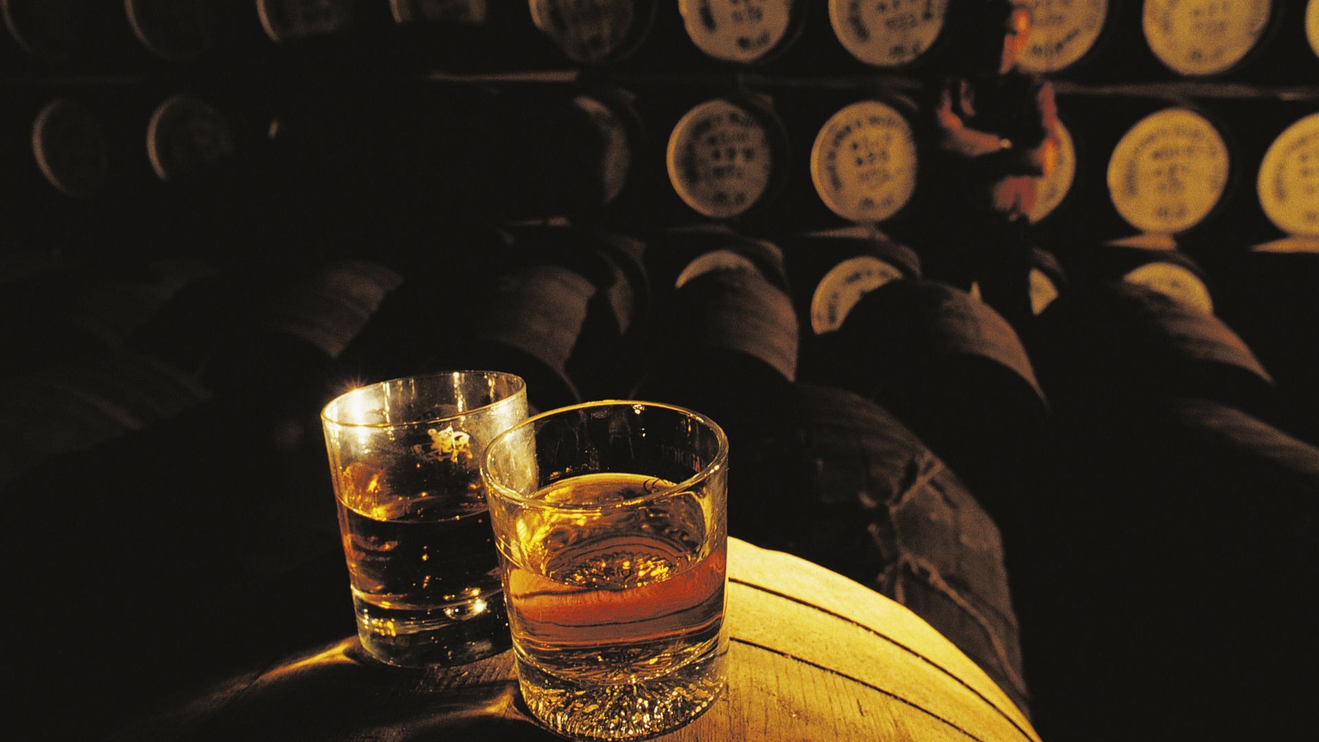 Glasses of whiskey on barrels.