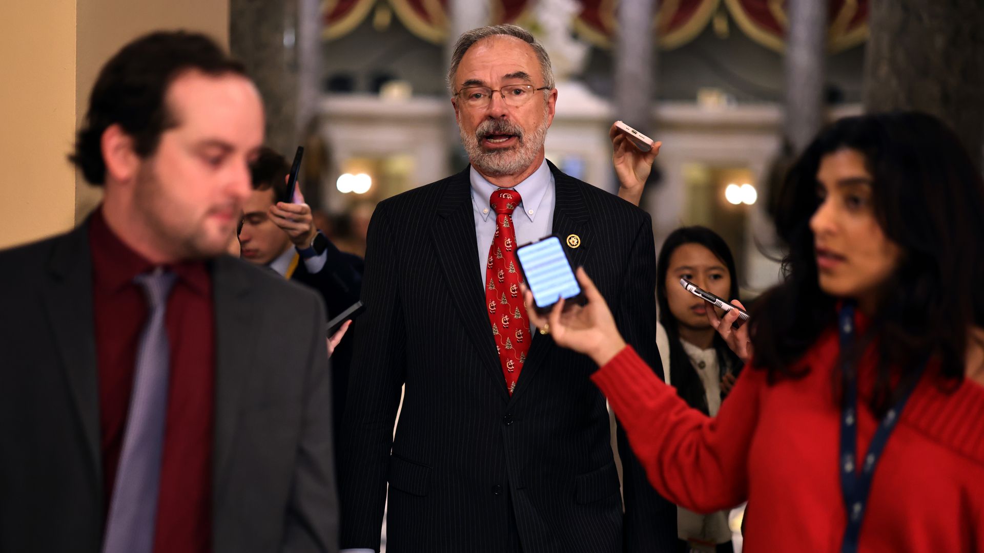 Rep. Andy Harris wearing a black suit and walking through a hallway while being interviewed by reporters.