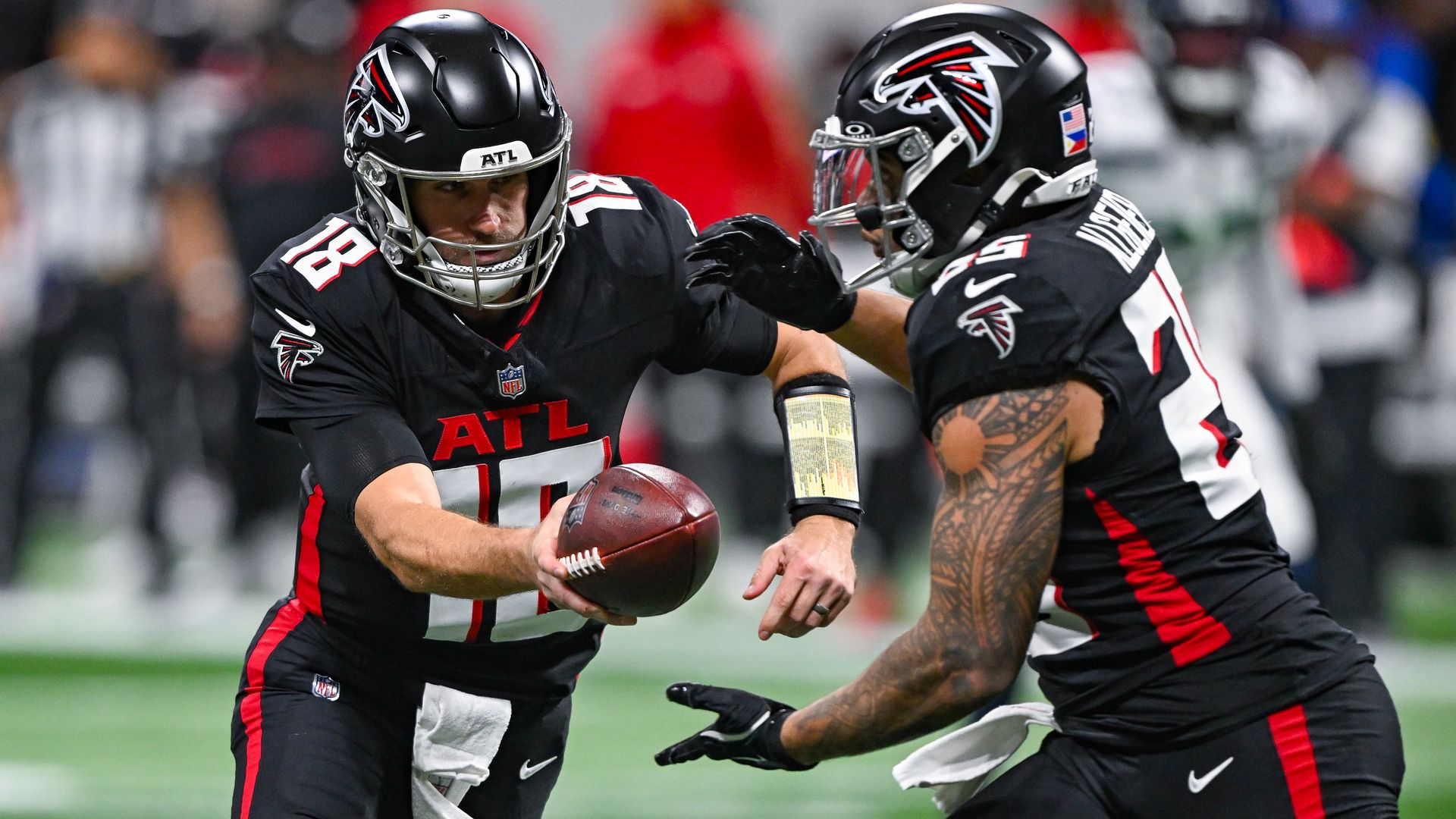 Atlanta quarterback Kirk Cousins, left, hands off to running back Tyler Allgeier during an NFL game.