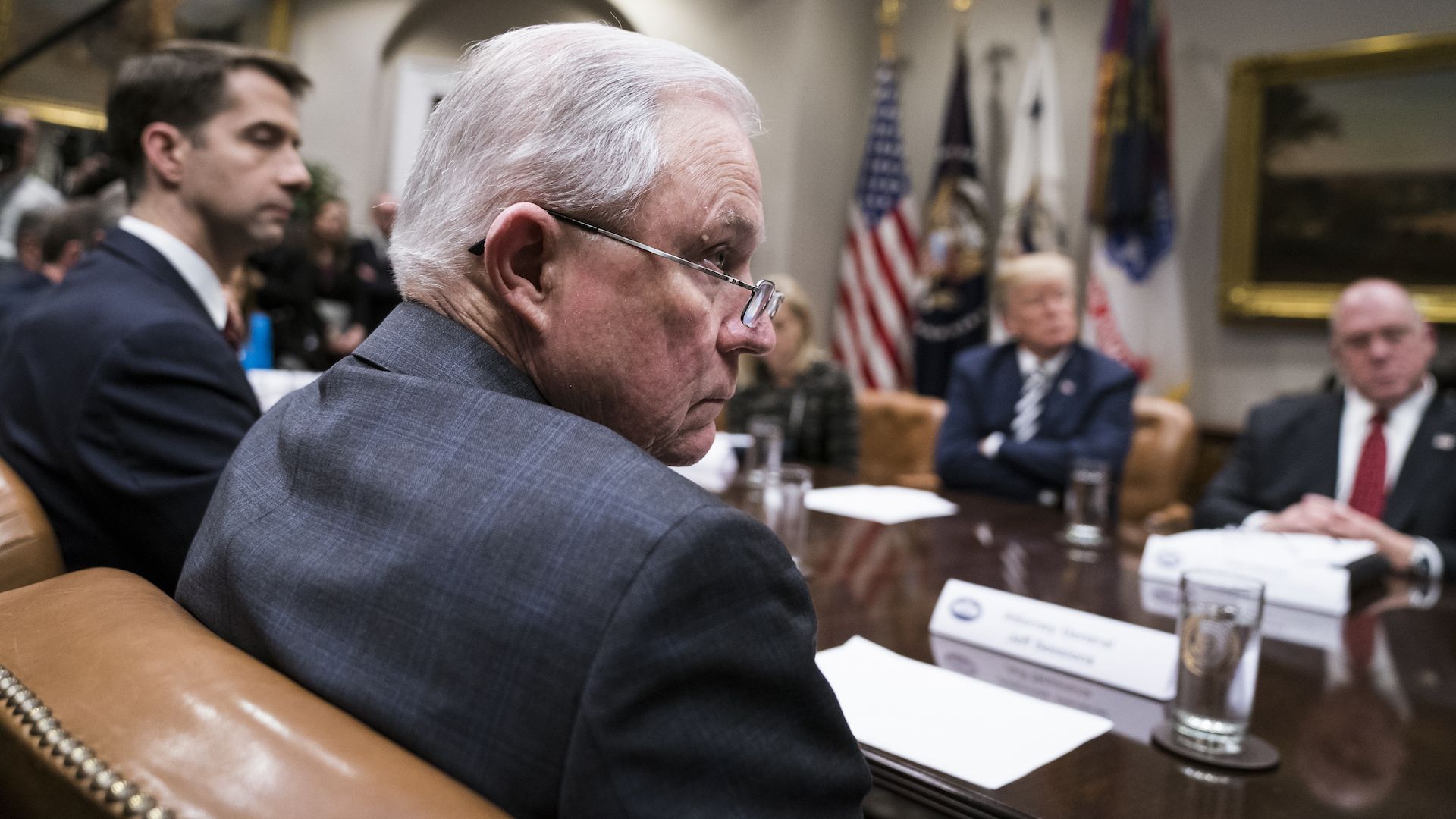 Jeff Sessions sitting at a desk and his glasses down on his nose