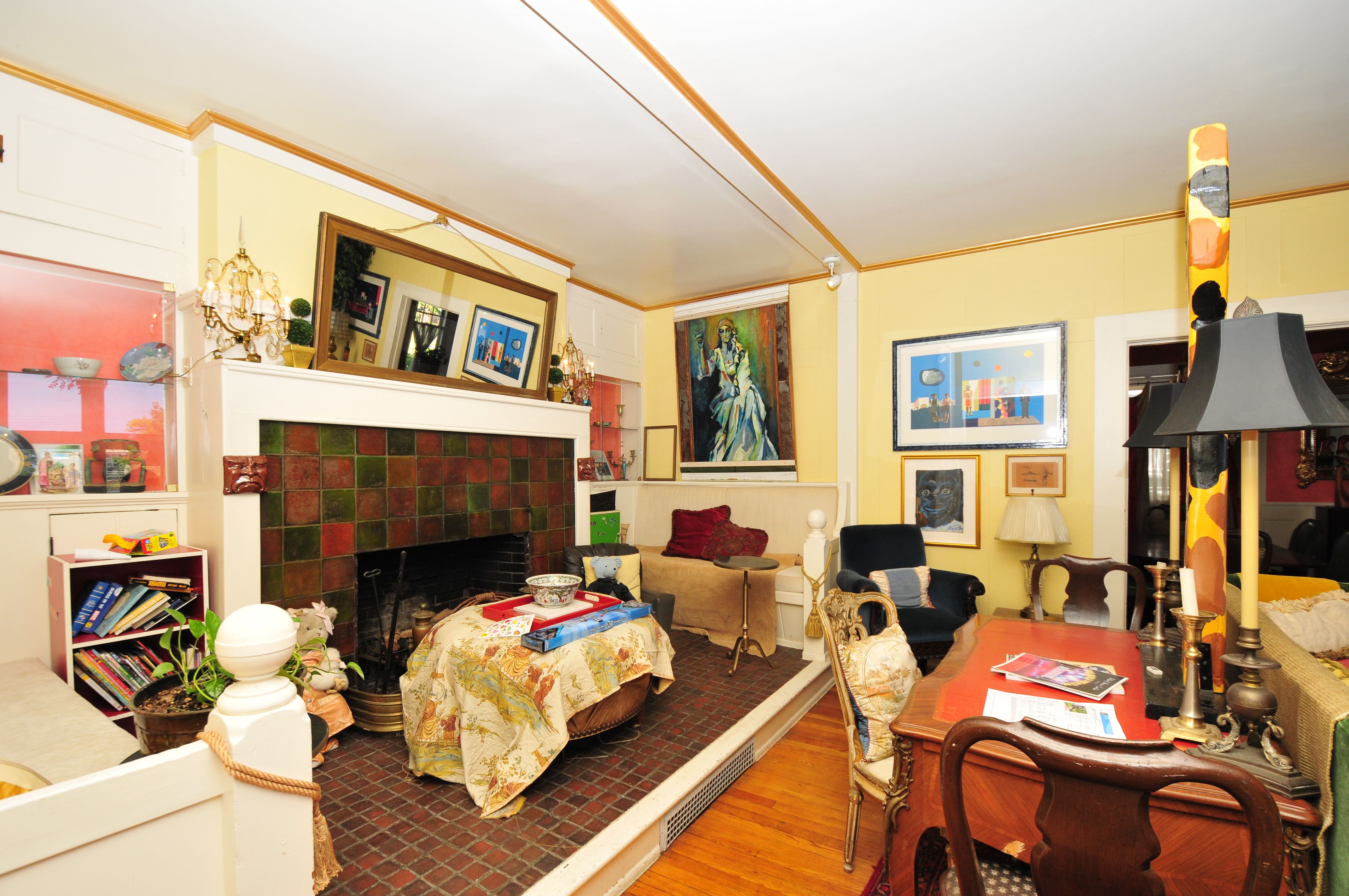 The interior of the home with yellow walls, a detailed fireplace and furniture inside.