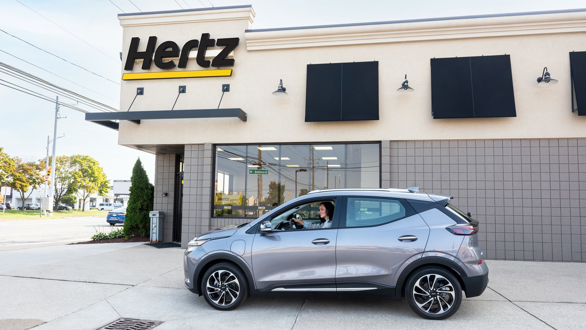 A Chevy Bolt EUV beside a Hertz car rental office.