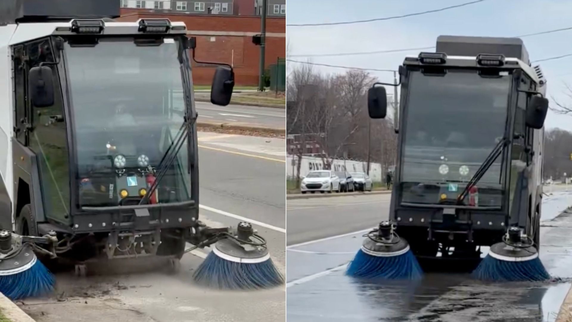 A street-sweeping truck with two large blue brushes at the front, cleaning debris from a city street; windshield and side mirrors visible, with parked cars and buildings in the background.