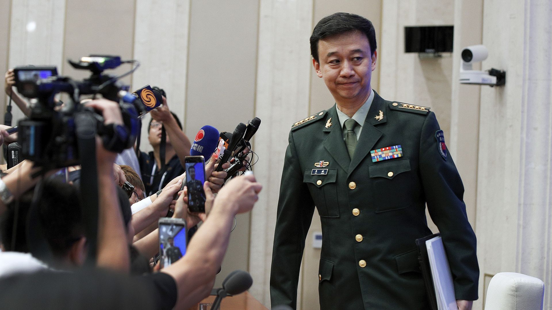 China's Defense Ministry spokesman Wu Qian leaves as journalists are asking question at a press conference at the State Council Information Office in Beijing, Wednesday, July 24.