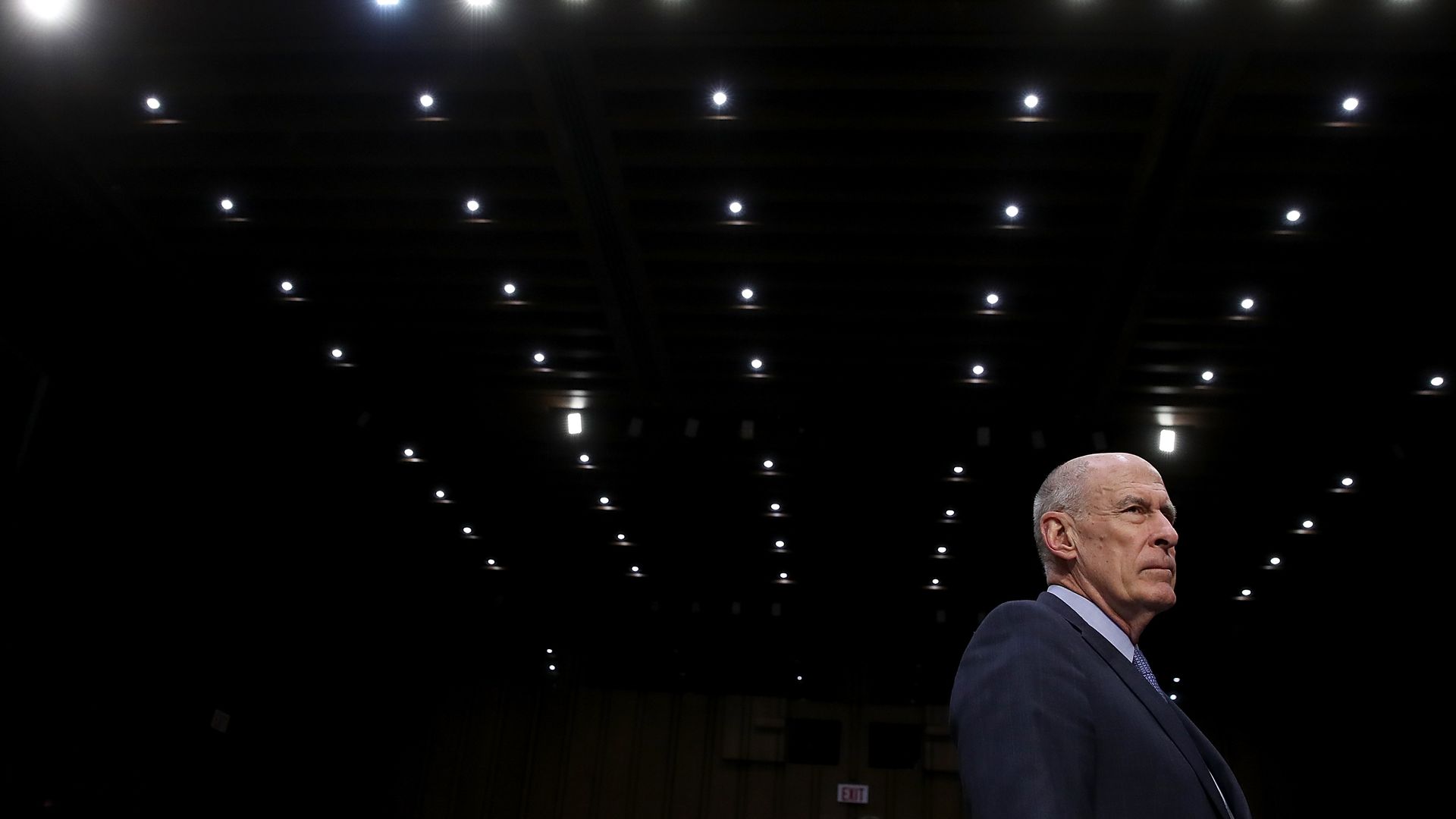 Coats stands alone in a dimly lit Senate chamber