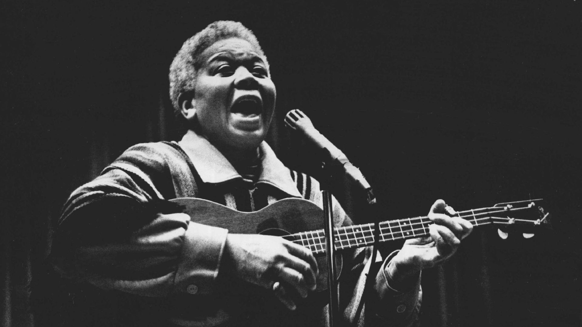 Woman singing with guitar in hand 