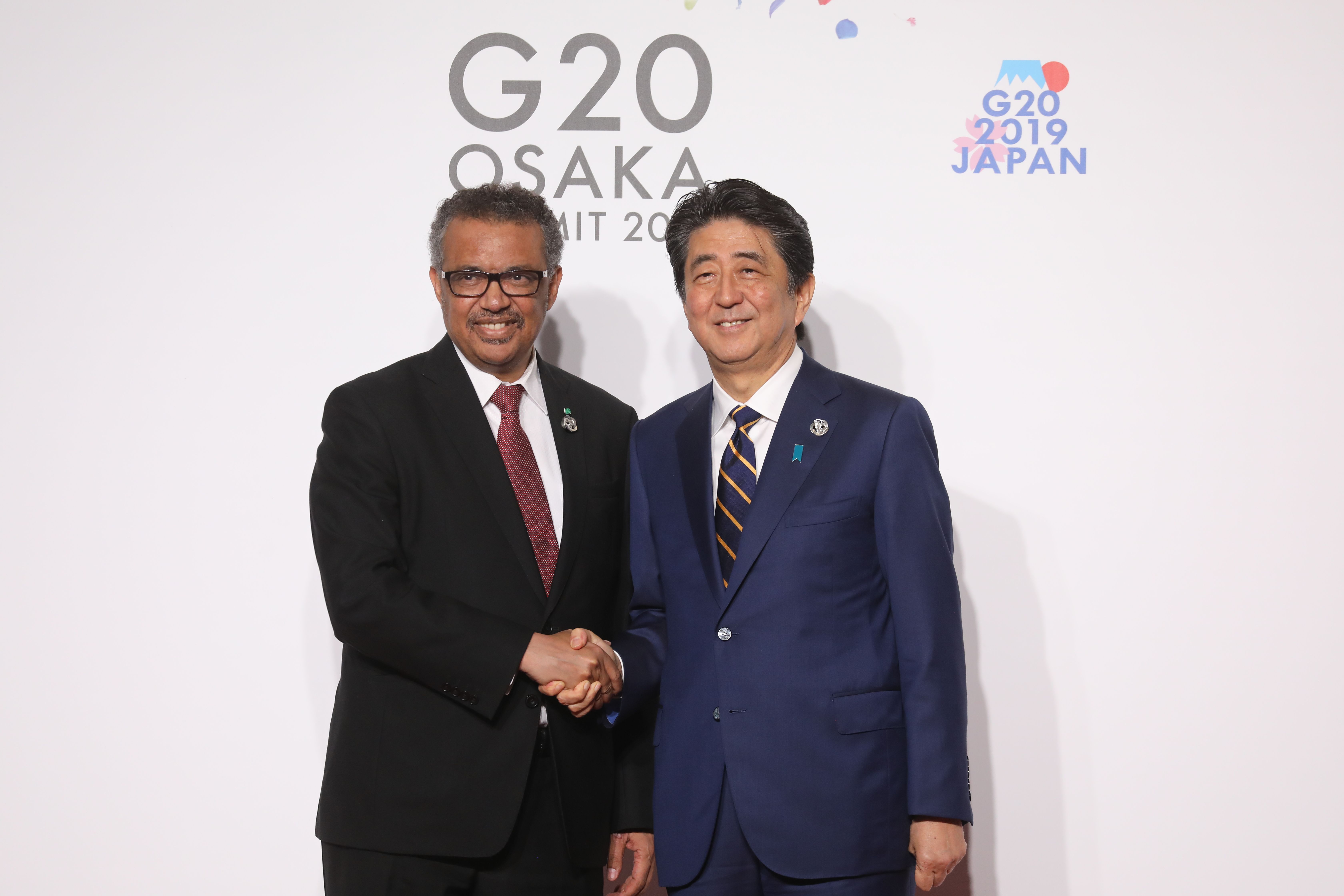 World Health Organization director general Tedros Adhanom is welcomed by Japanese Prime Minister Shinzo Abe prior to the family photo at the G20 Osaka Summit in Osaka on June 28, 2019.