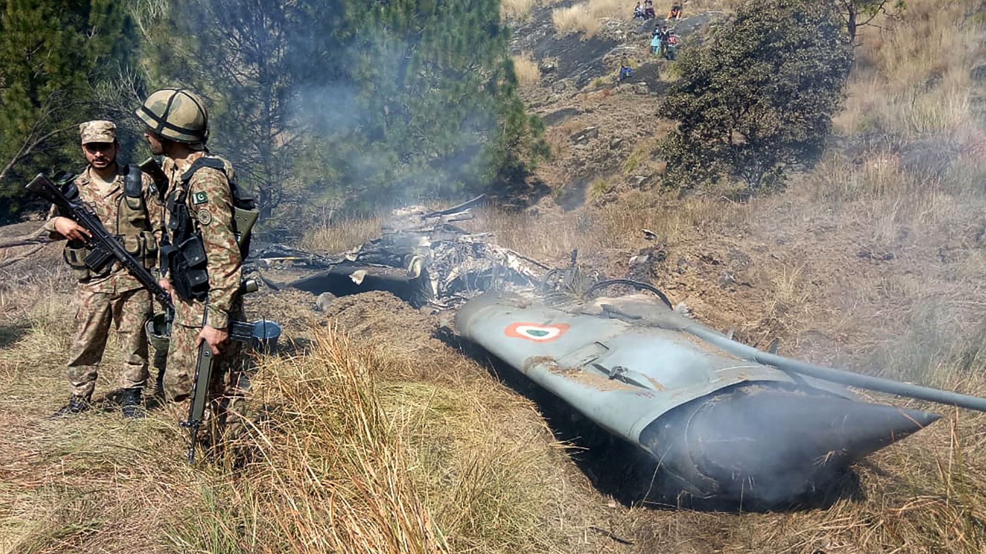 Pakistani soldiers stand next to what Pakistan says is the wreckage of an Indian fighter jet shot down in Pakistan controled Kashmir at Somani area in Bhimbar district