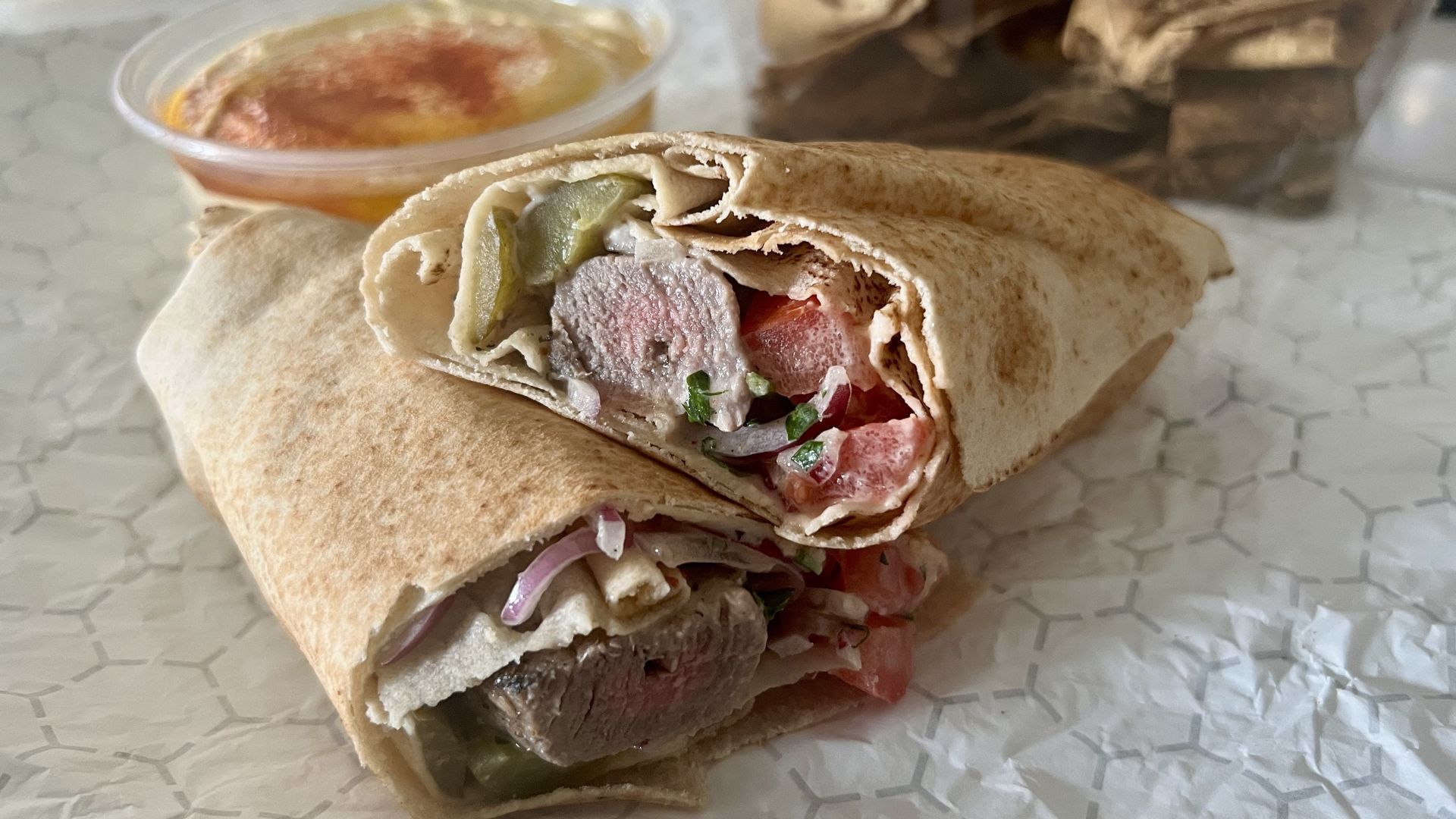 A wrap with beef, tomatoes and onions inside it