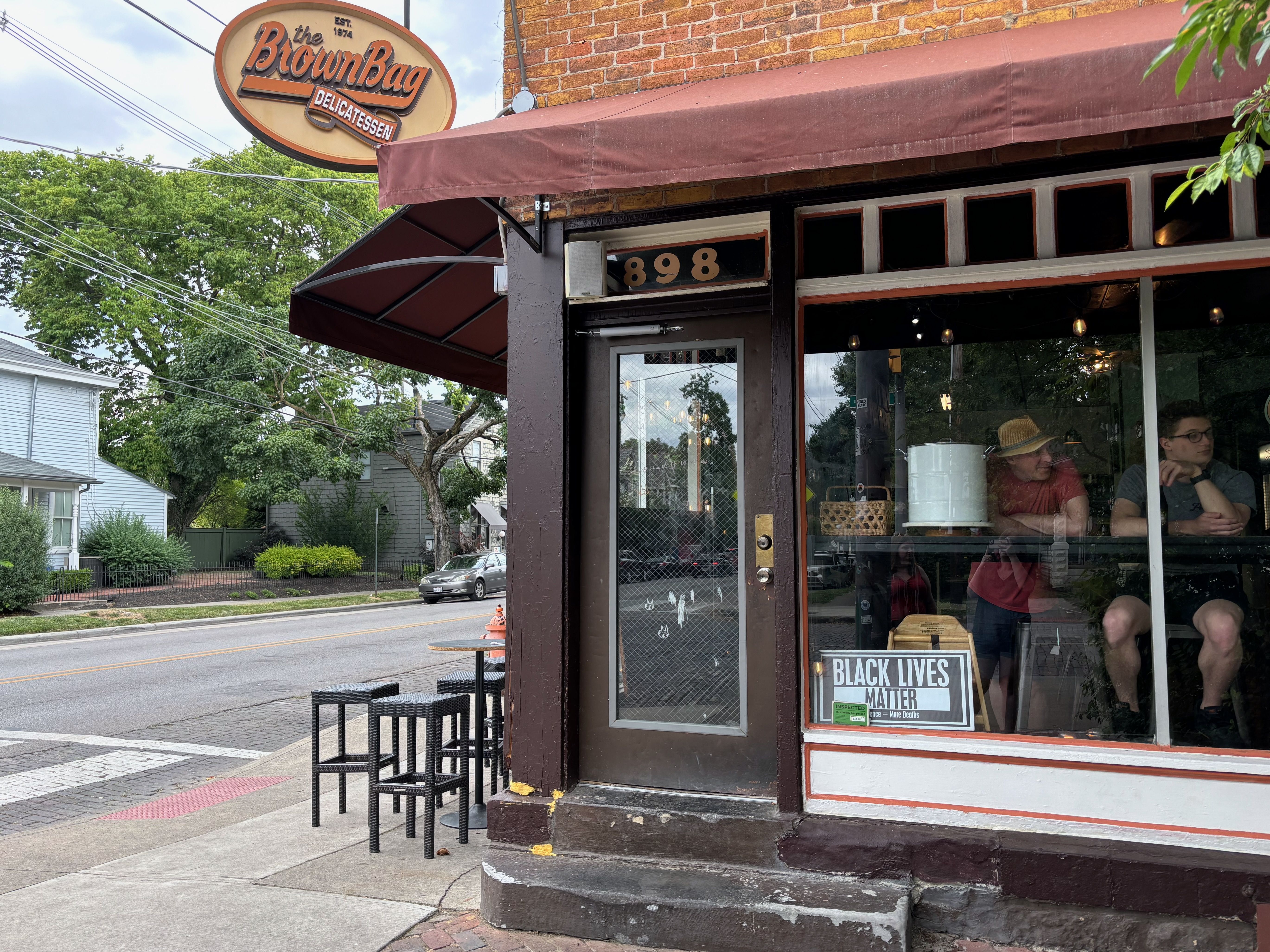 The front entrance to the Brown Bag Delicatessen, on a street corner, with a dark brown awning