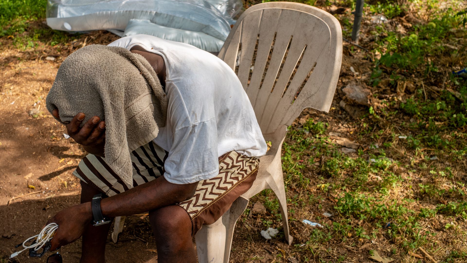 Dymond Black sits with a towel over his head in the shade on June 19, 2023 in Austin, Texas.