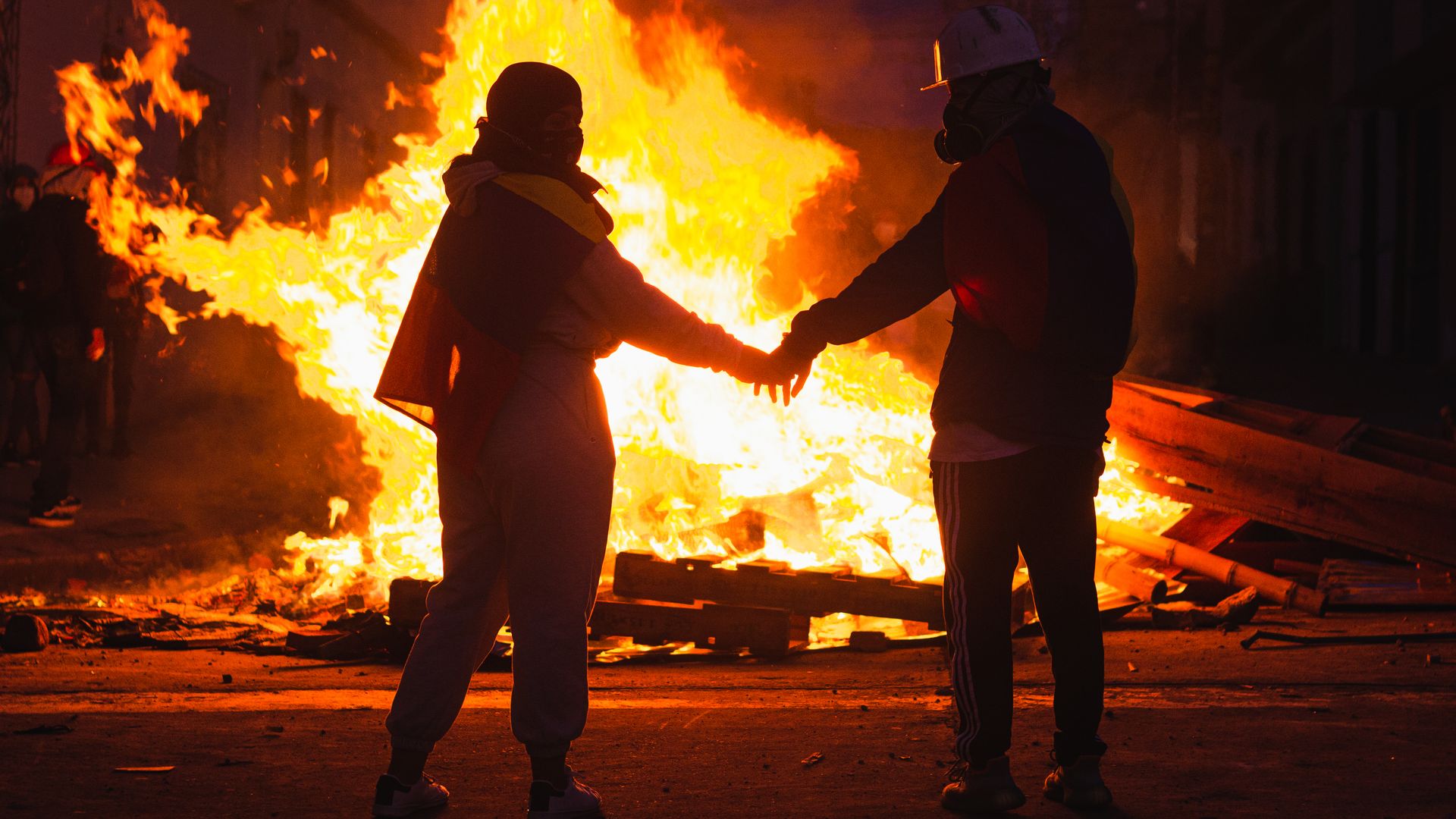 A couple stands before as fire during street protests in Colombia.