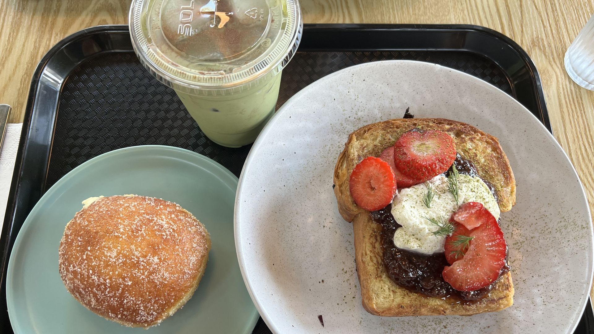 Photo of a tray with a matcha drink, french toast and a pastry