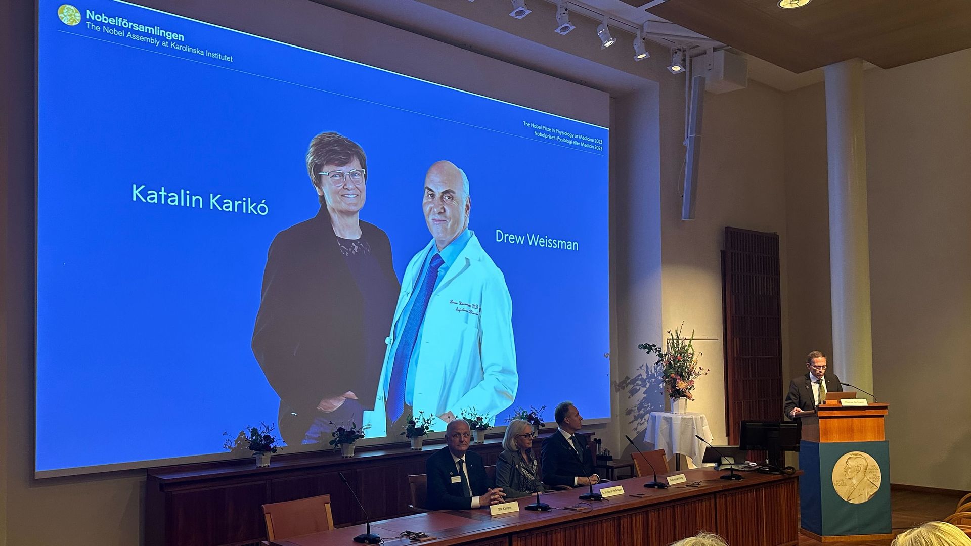 Photos of scientist Katalin Karikó and scientist Drew Weissman are shown on a screen during the announcement of the Nobel Prize in Medicine today in Stockholm.