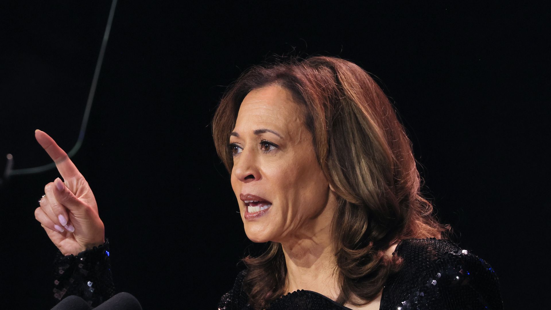 Vice President Kamala Harris raises her index finger while making a point during a speech.
