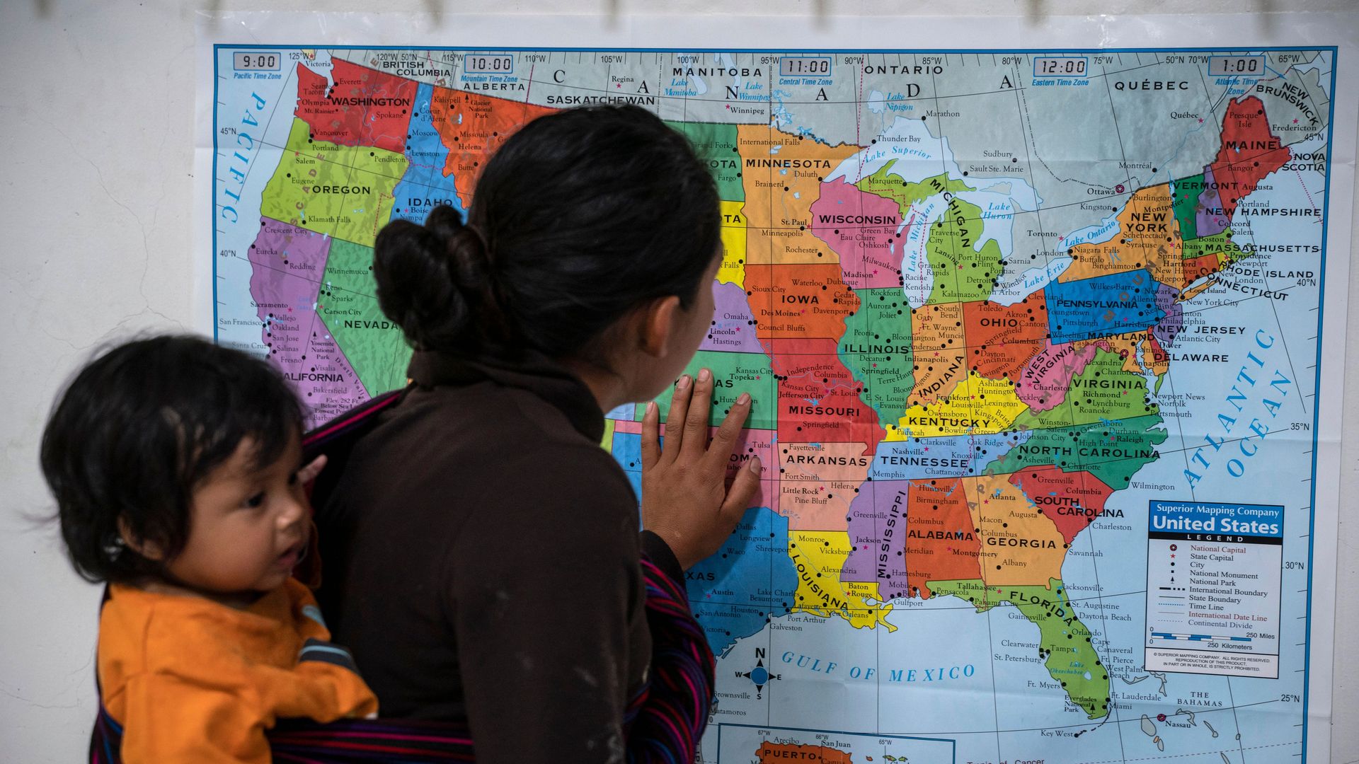 Guatemalan woman looking at a map of the U.S. with her baby