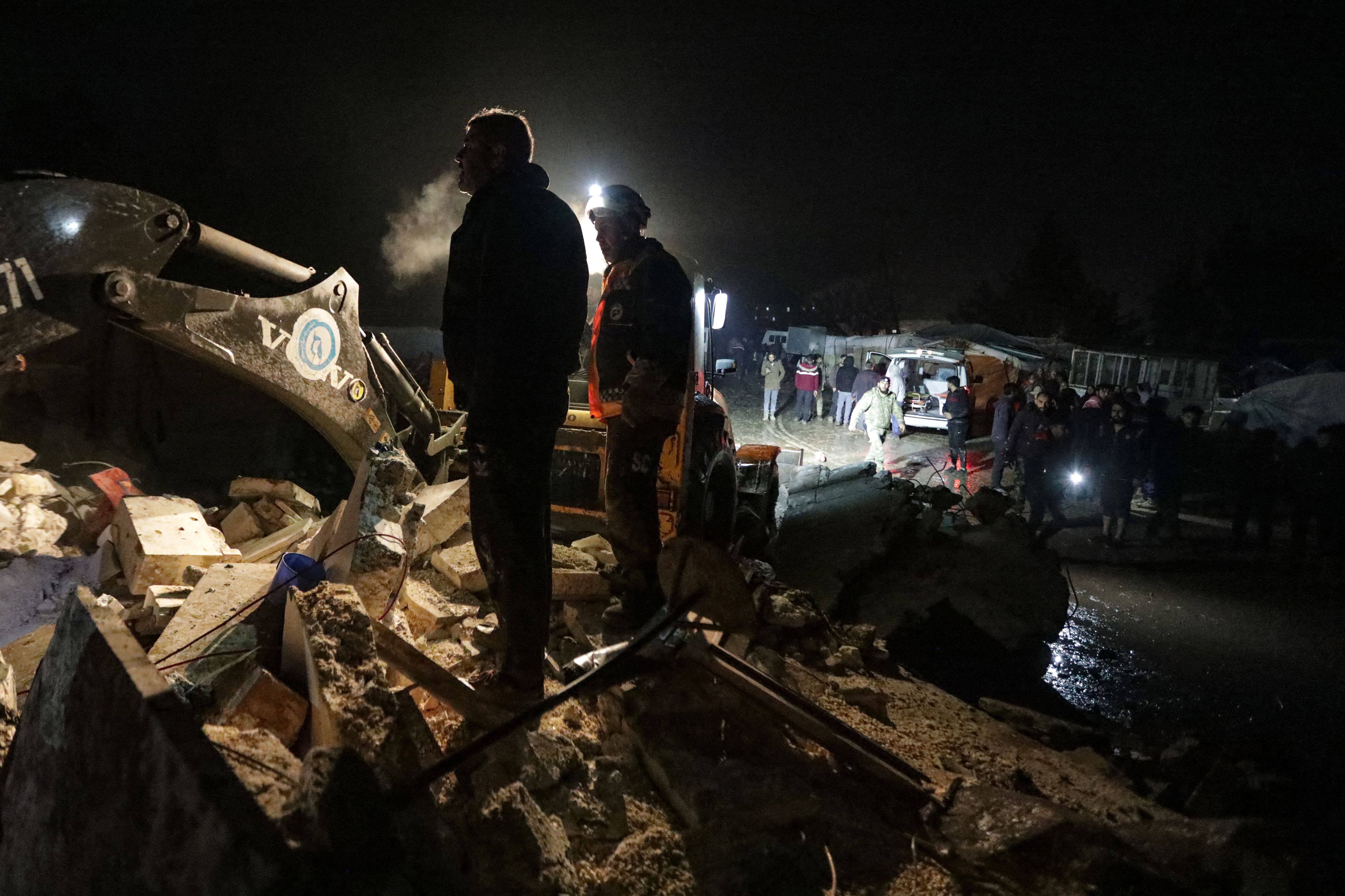 Syrian rescuers (White Helmets) and residents gather near a collapsed building following an earthquake, in the border town of Azaz in the rebel-held north of the Aleppo province, early on February 6.