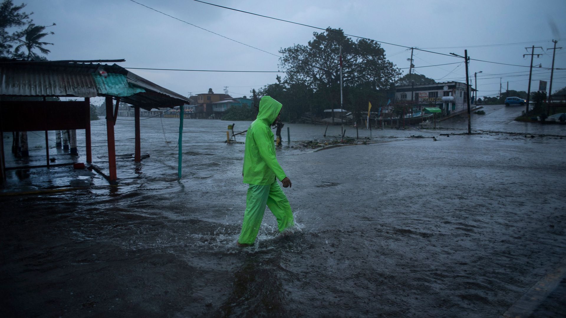 Picture of a man in a neon raincoat walking through a flooded area in Mexico