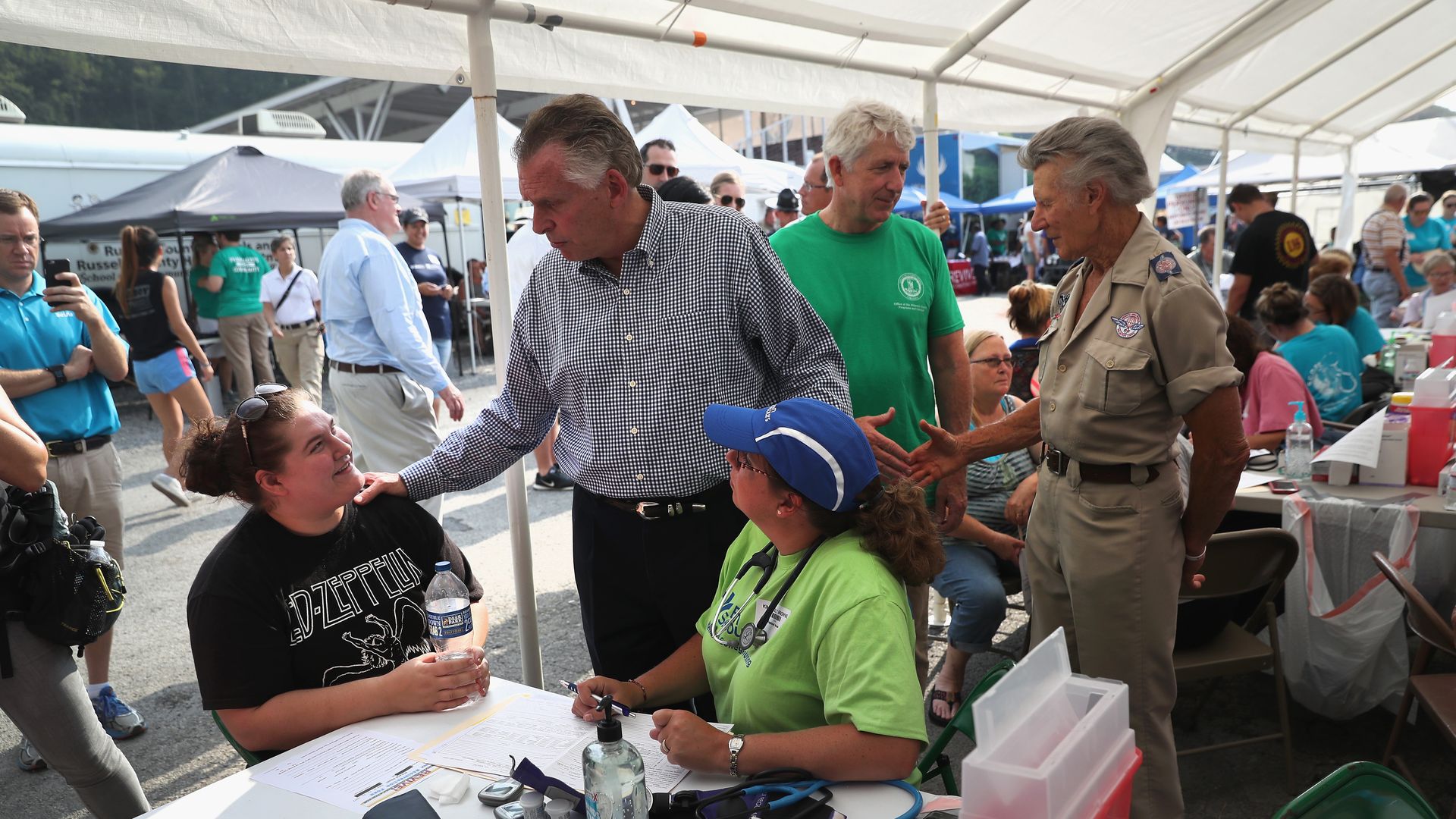 Patients sit under a tent at a free medical clinic.